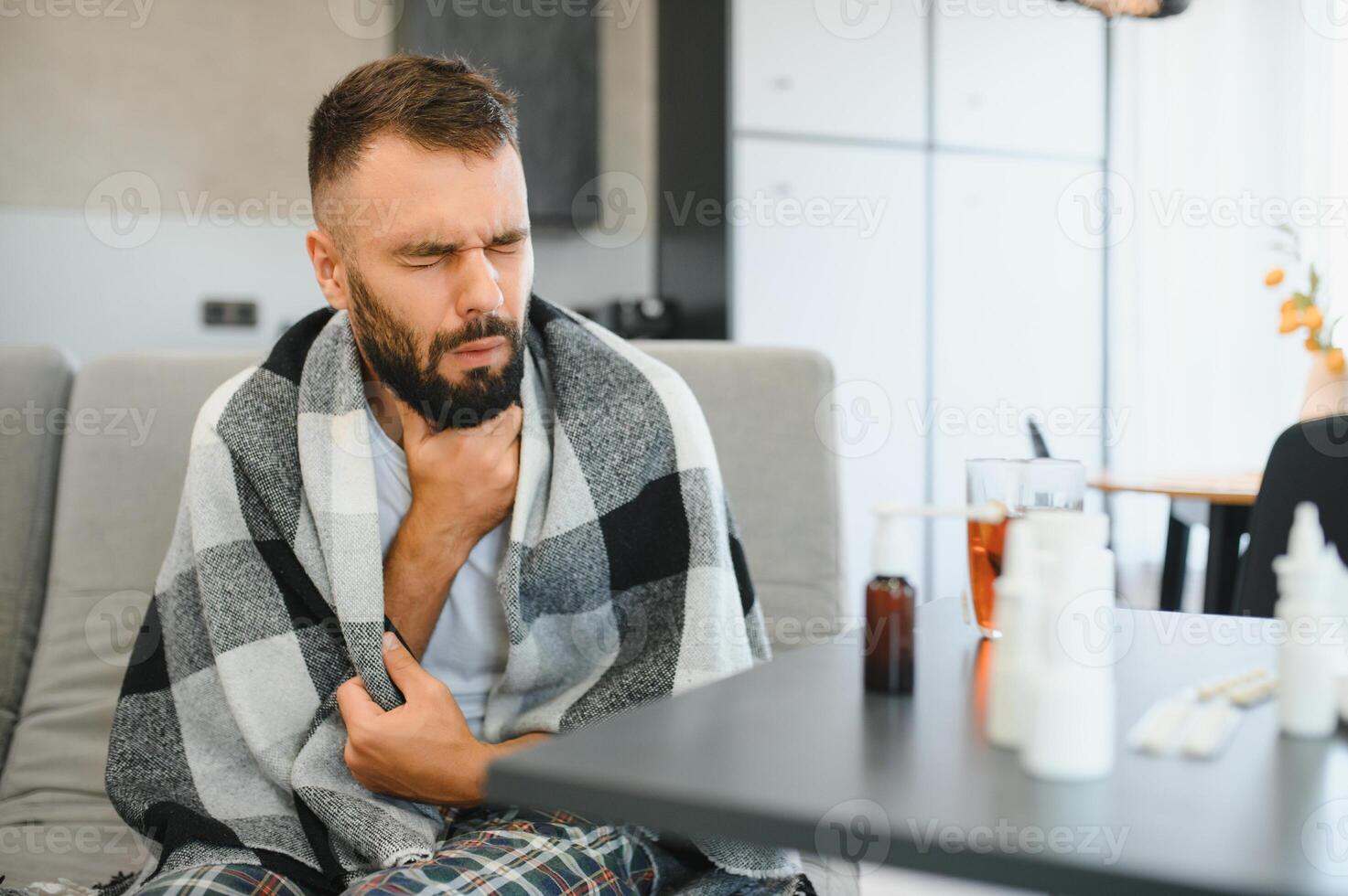 Sick man holding his chest in pain while coughing in the living room. Sore throat and cough, man with lung pain at home, health problems concept photo