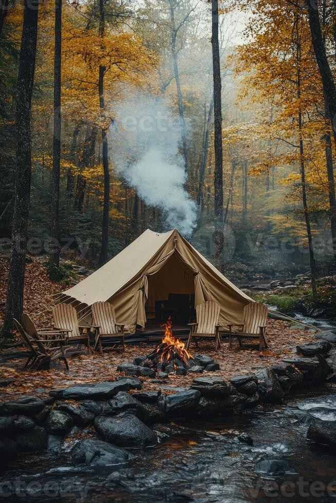 Smoke rising from campfire in front of tent near river in autumn forest photo
