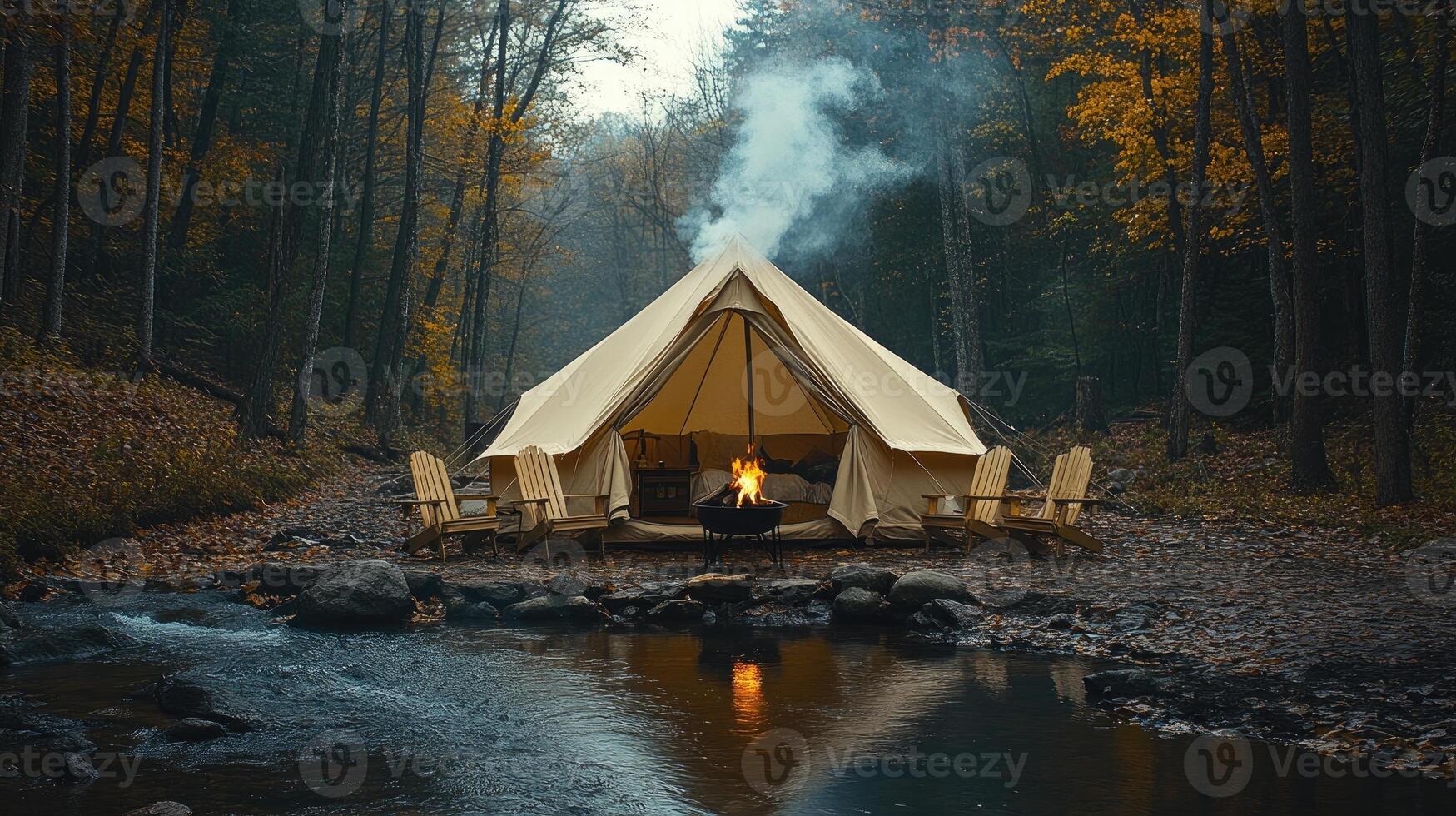 Smoke rising from campfire in front of tent near river in autumn forest photo