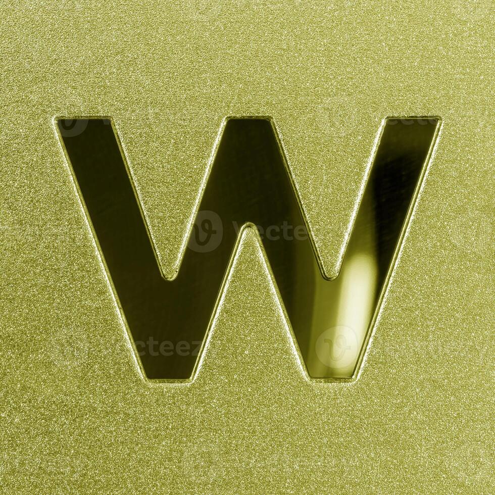 Letter W on a golden grained shiny metal surface. English alphabet. photo