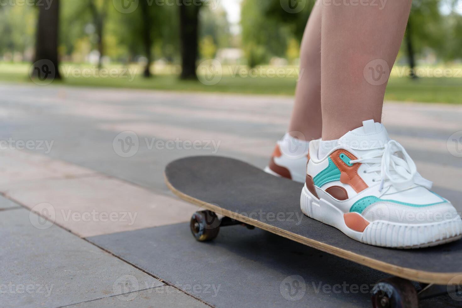 Low-angle snapshot of a teenager's light-colored shoes steadily balanced on a skateboard, conveying the adventurous, carefree nature of warm weather recreation photo