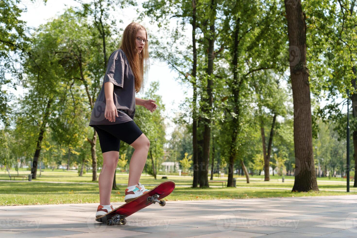 Young female skateboarder in t-shirt enjoying freedom of movement in natural setting. Representing active, adventurous lifestyle of teenagers during warm weather photo
