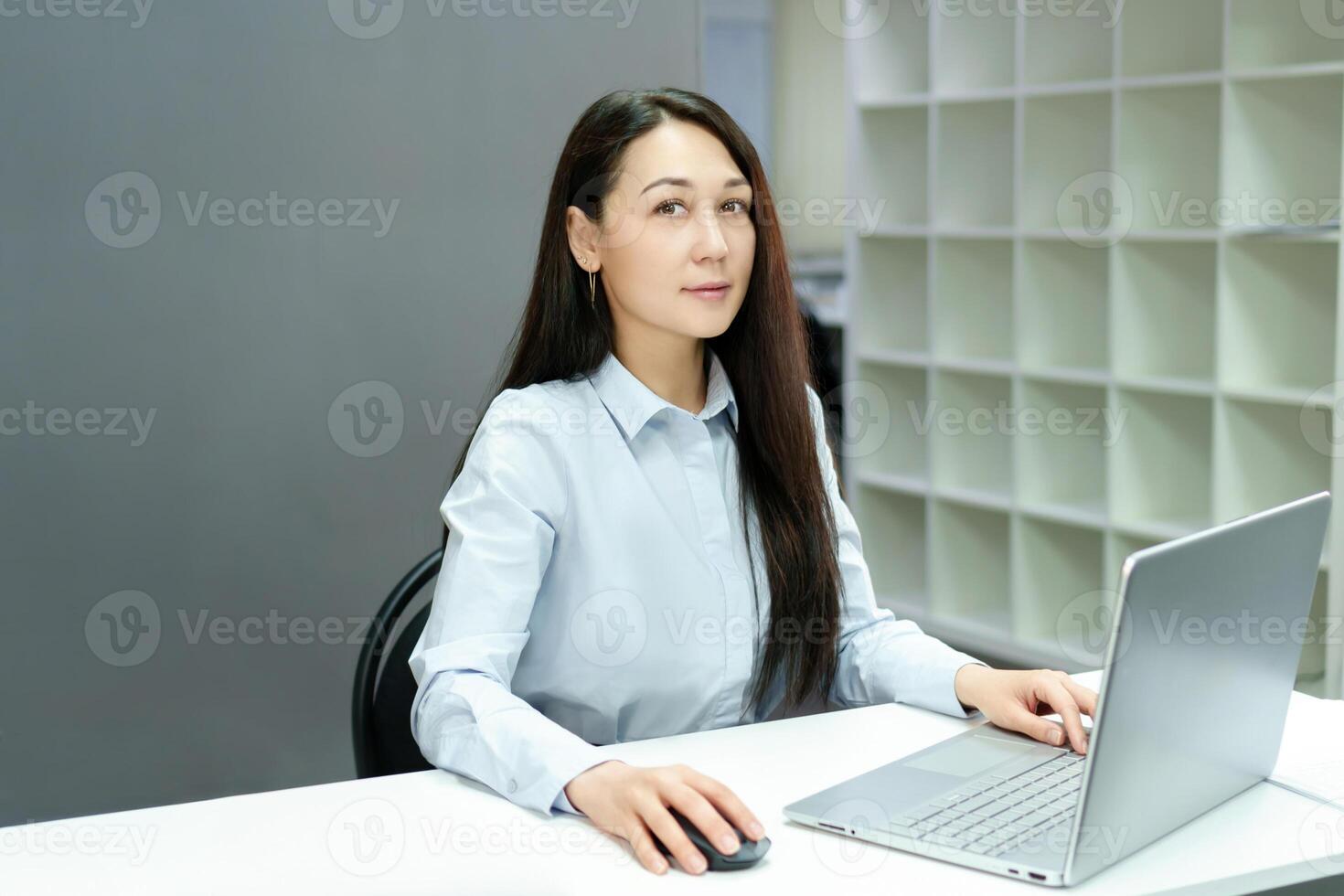 confident young woman spends her workday in a modern office, sitting at a desk and successfully completing tasks on a computer photo