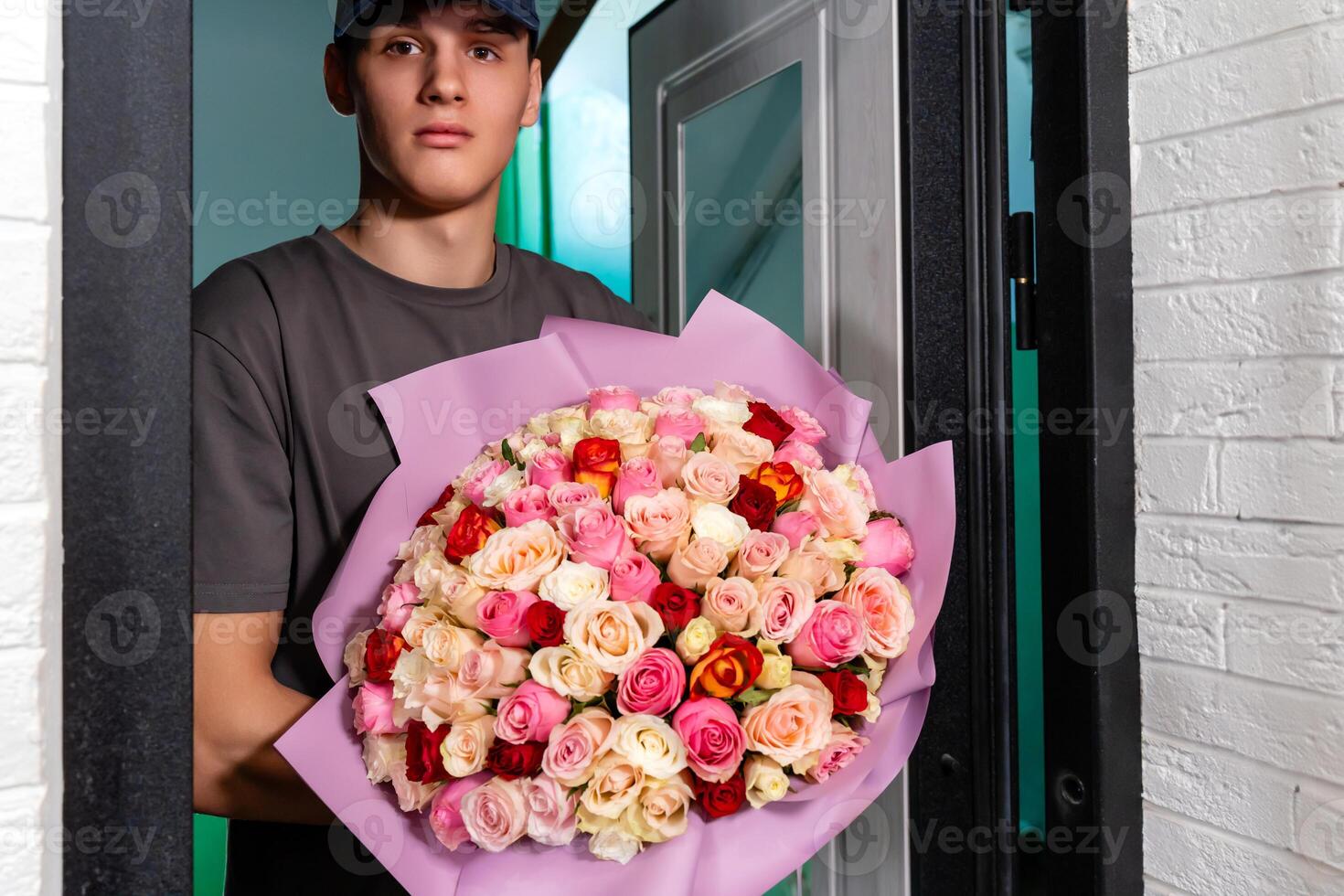 Delivery man with beautiful from multi-colored roses bouquet in the door, closeup photo