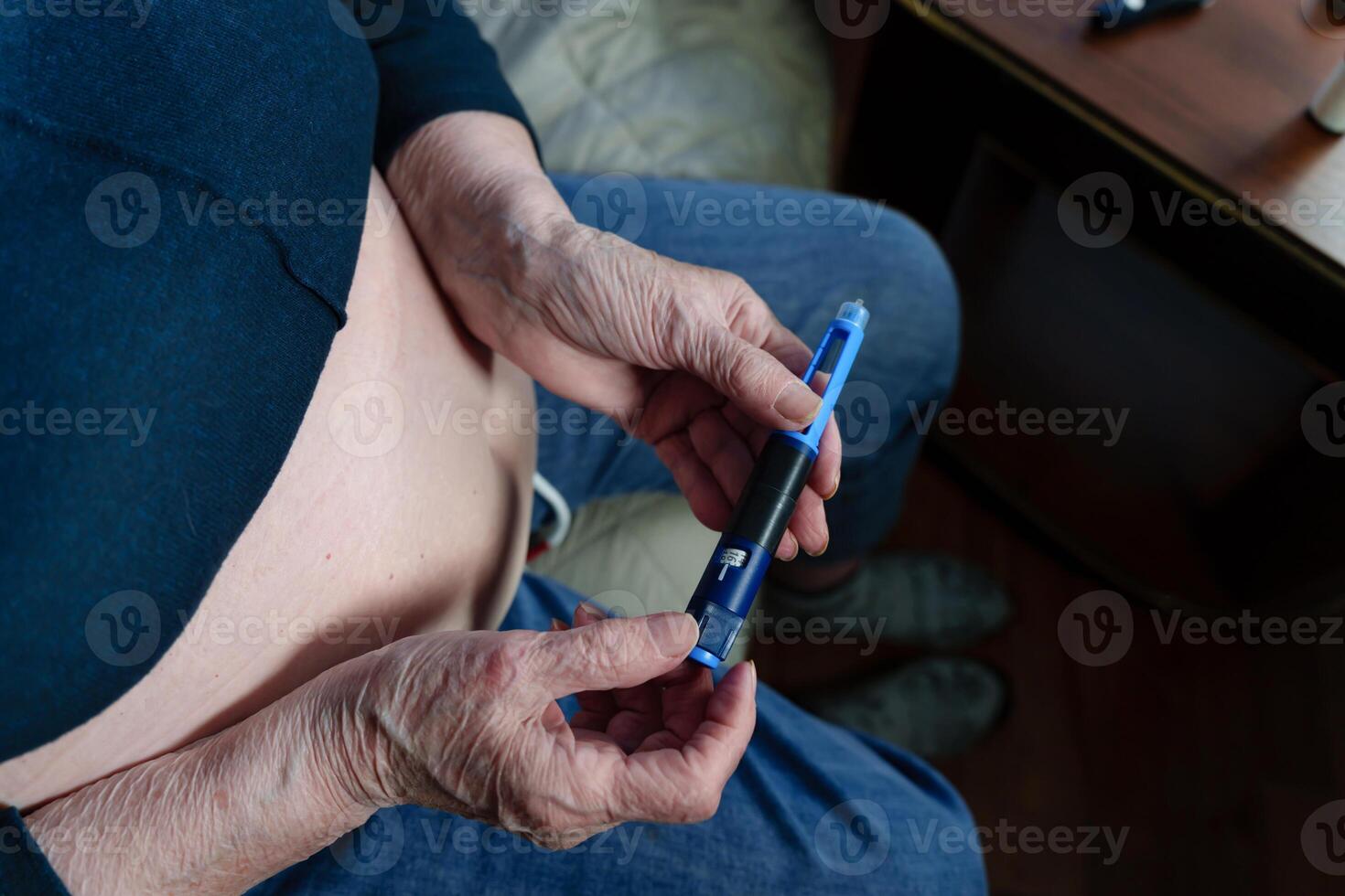 wrinkled fingers of an elderly person delicately hold an injection device, routine of insulin administration to control a chronic health condition photo