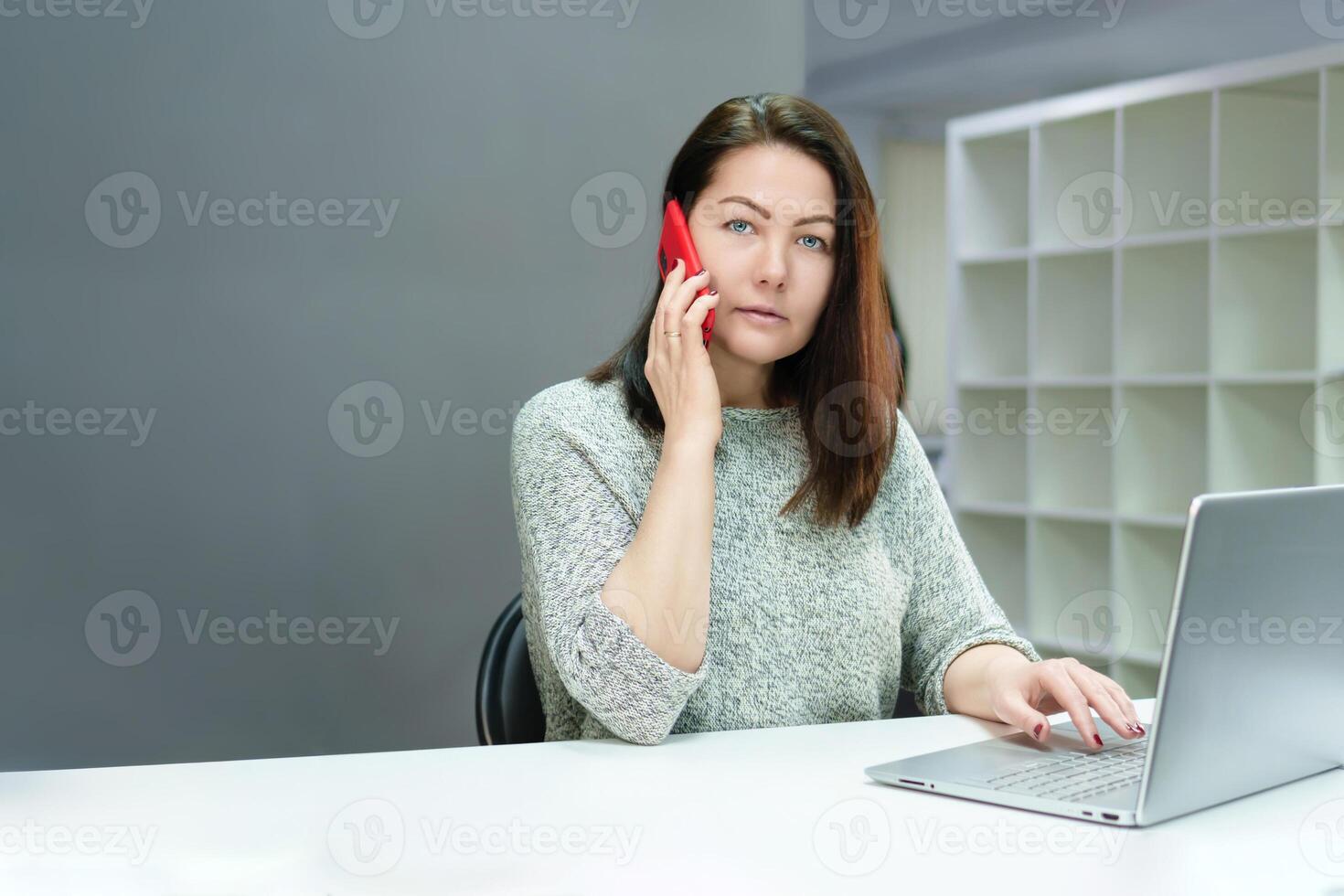 results-oriented young woman communicating on the phone while working at a computer in a modern office environment photo