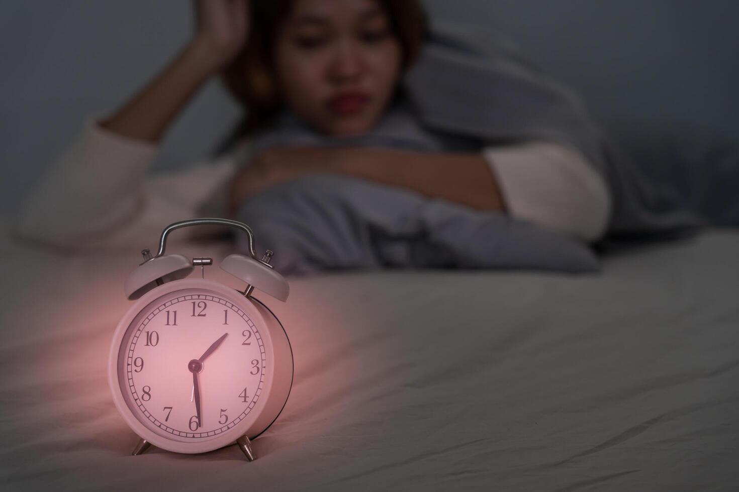 asian woman in bed late trying to sleep suffering insomnia, sleepless or scared in a nightmare, looking sad worried and stressed. Tired and headache or migraine waking up in the middle of the night. photo