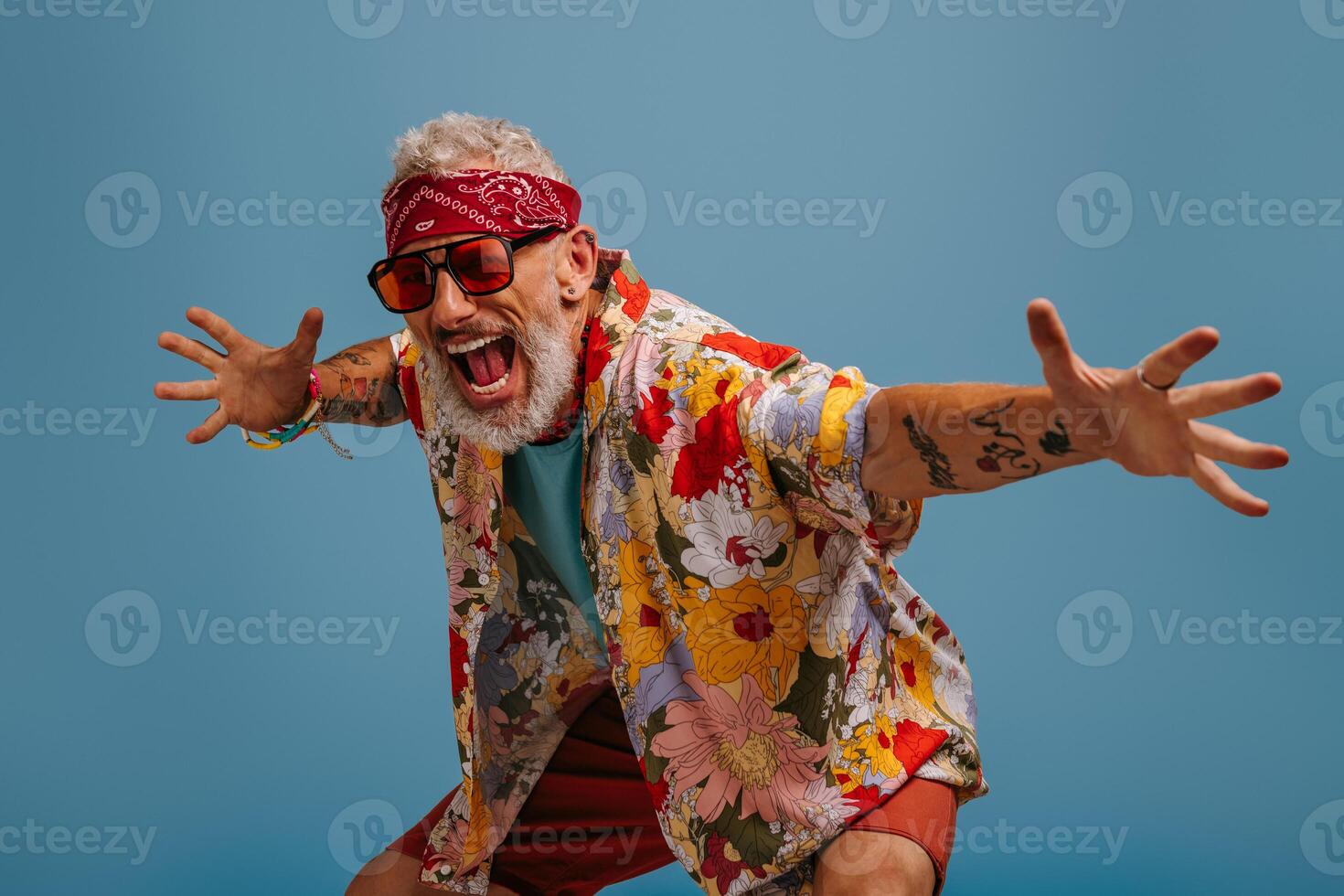Cool hipster senior man in stylish funky shirt gesturing and shouting against blue background photo