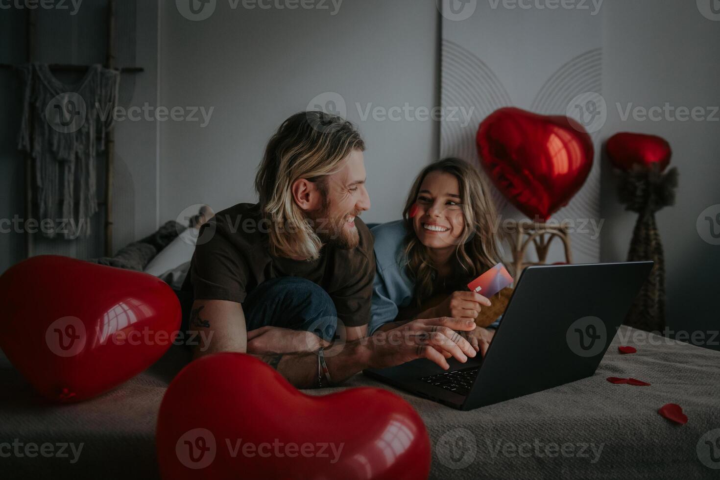 Happy loving couple using laptop and credit card while shopping online at Valentines day photo