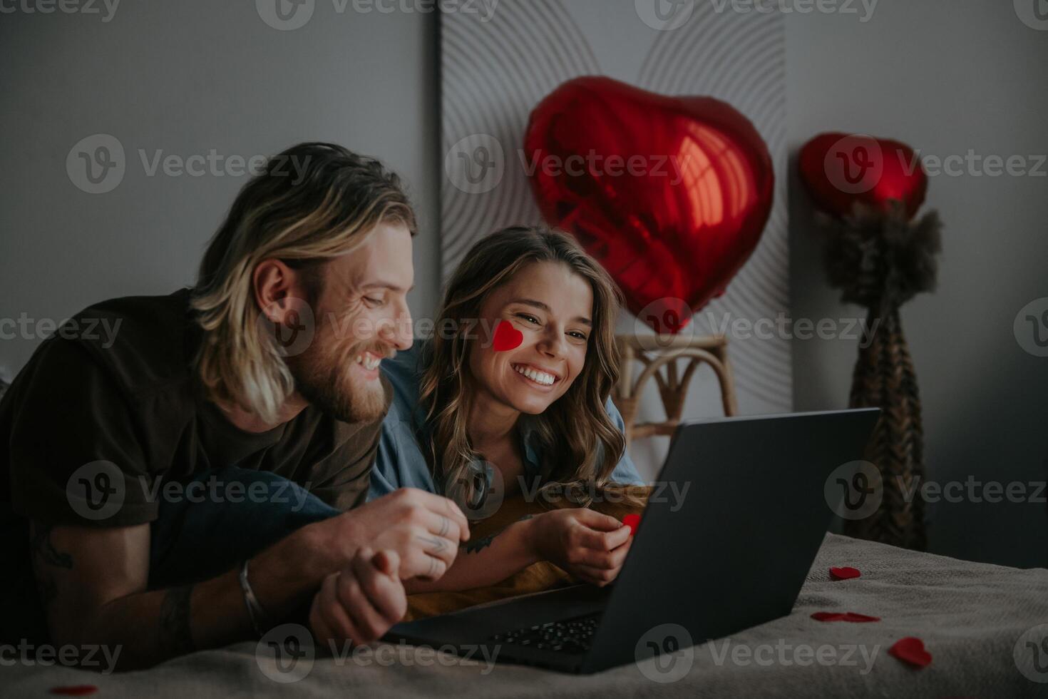 Joyful loving couple looking at laptop and using credit card while shopping online at Valentines day photo