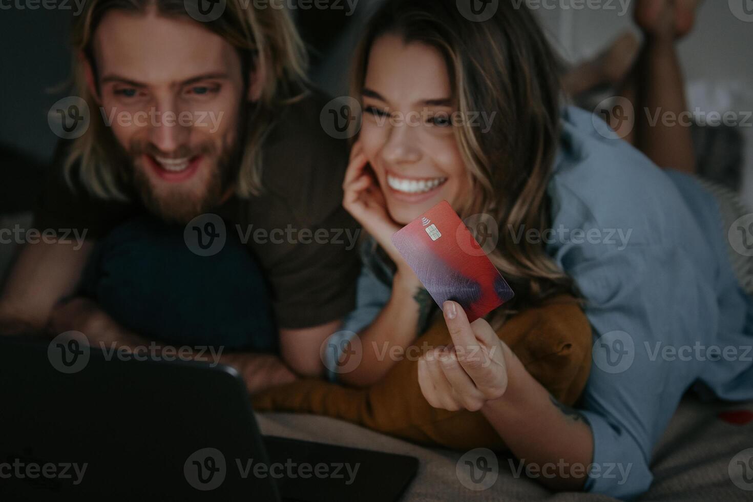 Happy loving couple looking at laptop and using credit card while shopping online from home photo