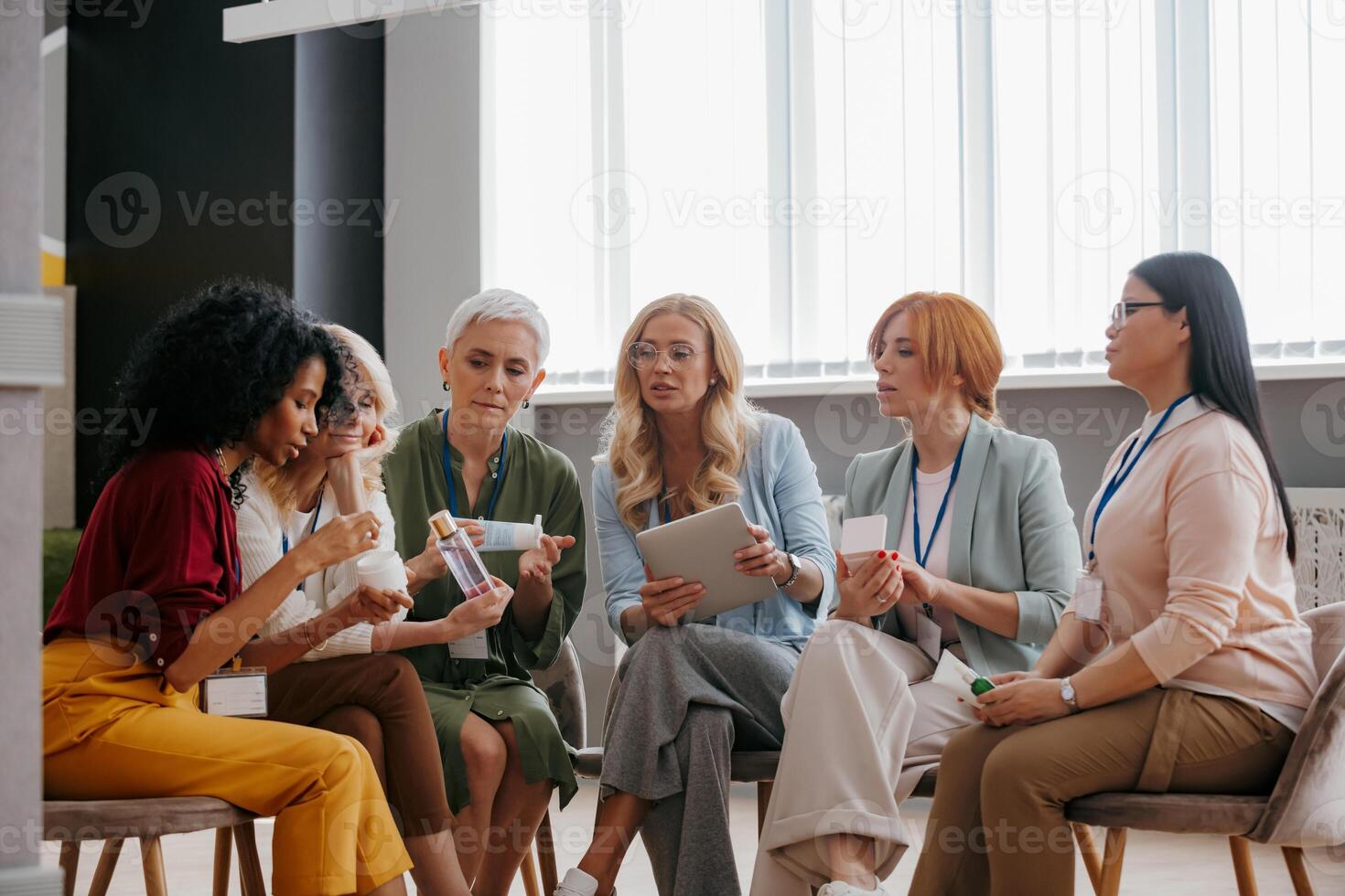 Group of confident mature women examining beauty products during specialized conference photo
