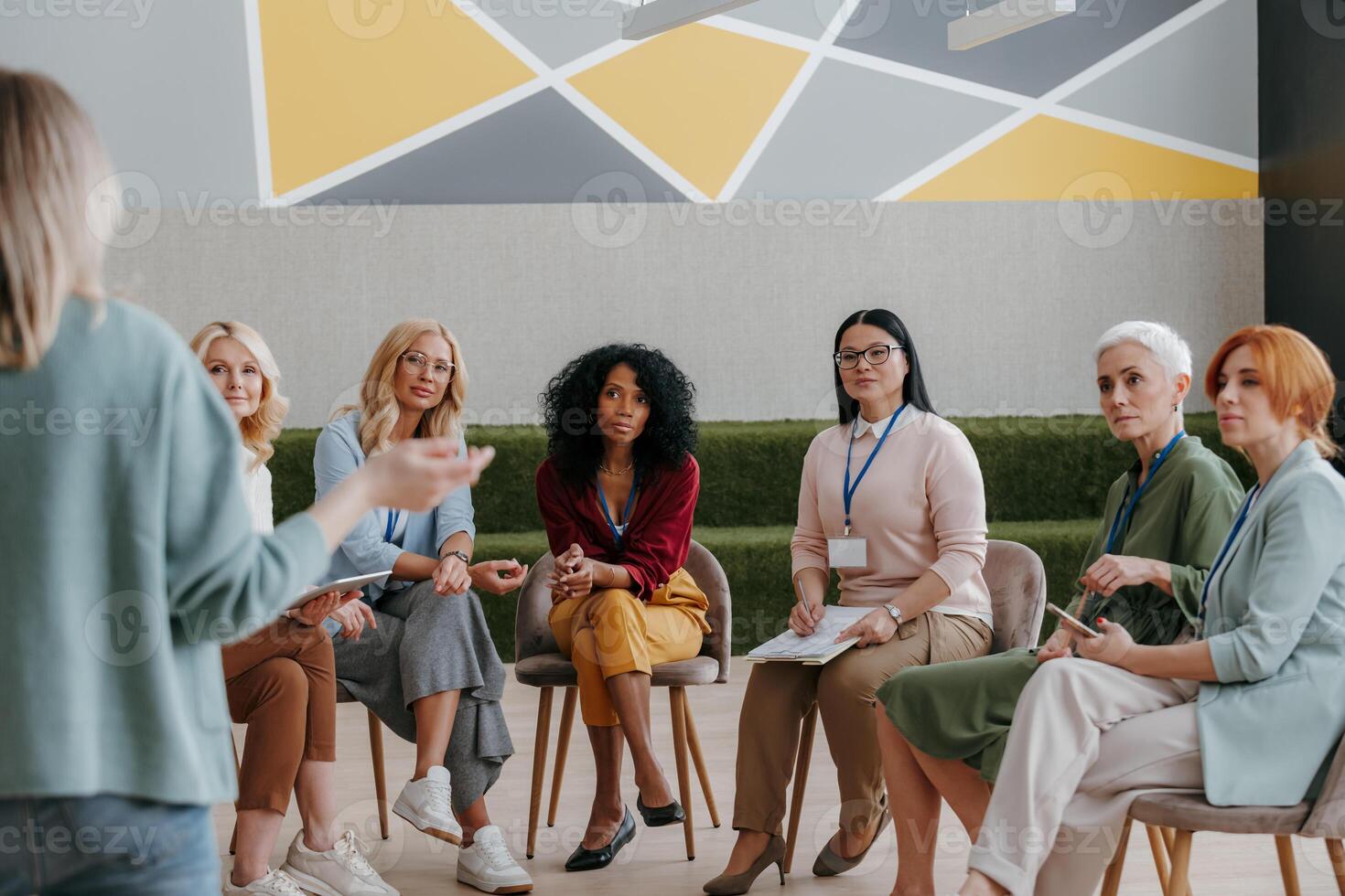 Group of confident mature women listening to speaker while visiting business conference photo