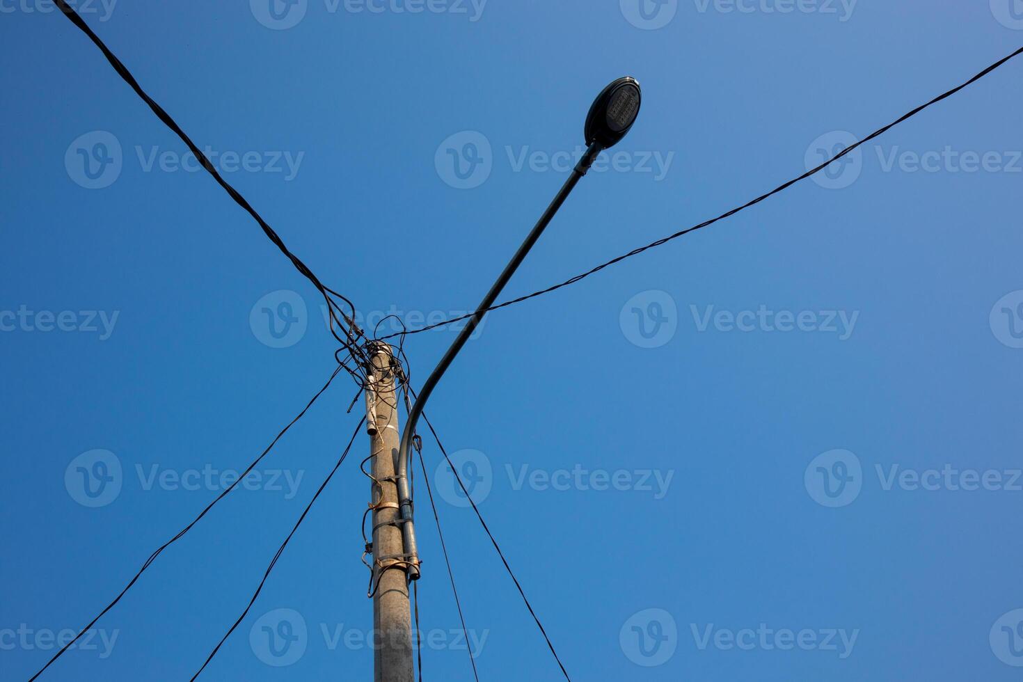 Photo of power pole under clear blue sky in the morning. Power pole photo with dangling wire. Power pole cable