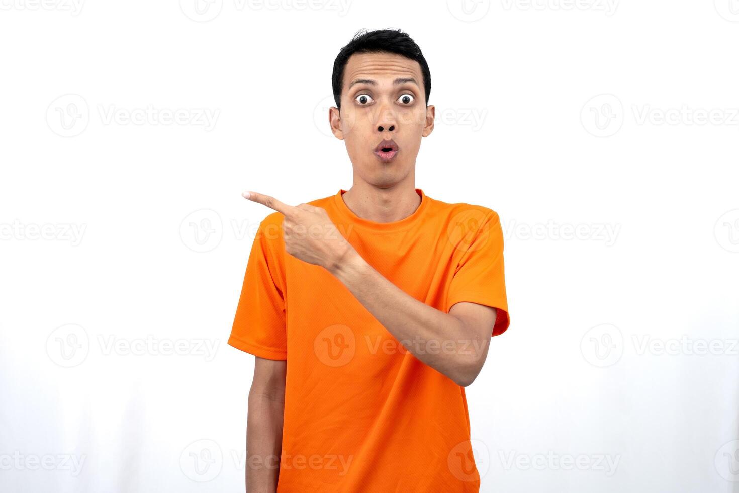 Portrait of a young Asian man wearing an orange t-shirt pointing aside copy space for promotional space. isolated on white background. photo