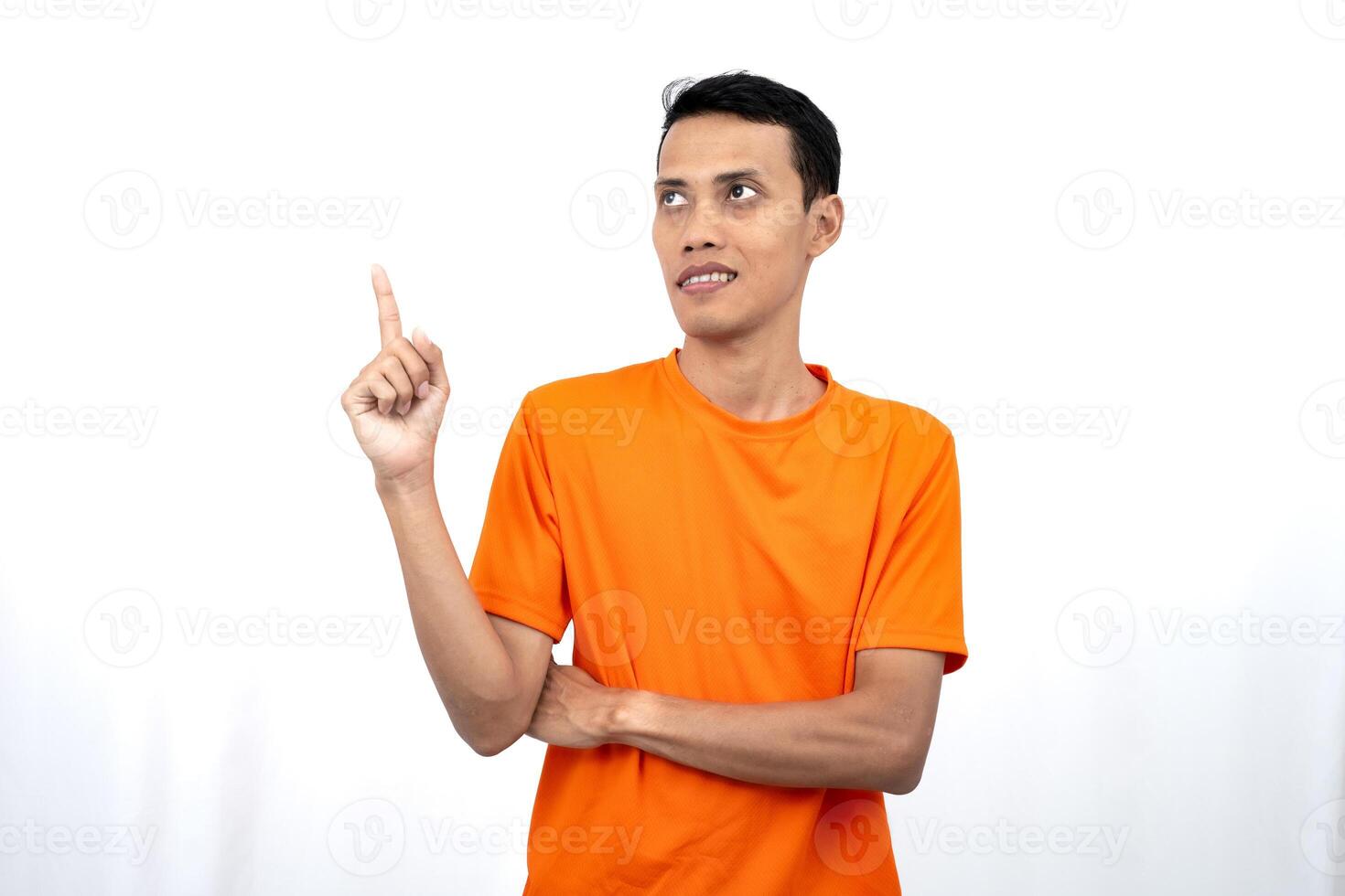 Portrait of a young Asian man wearing an orange t-shirt pointing upwards at copy space for promotional space. isolated on white background. photo