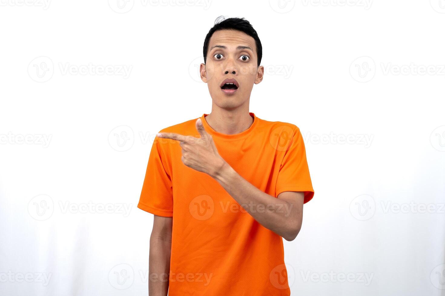 Portrait of a young Asian man wearing an orange t-shirt pointing aside copy space for promotional space. isolated on white background. photo