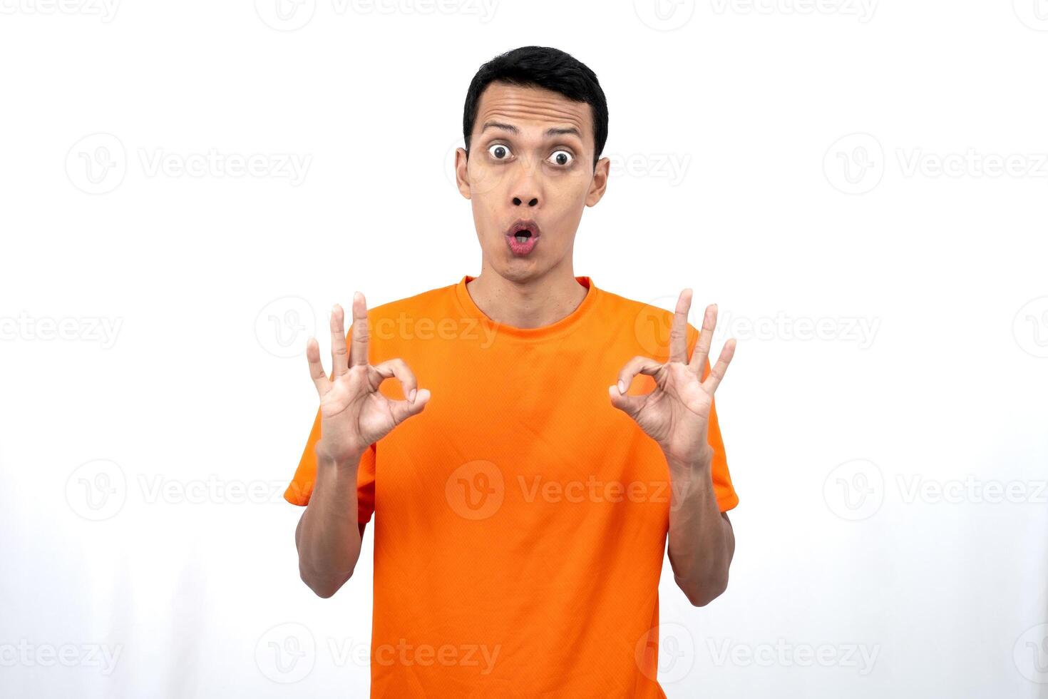 Portrait of a young Asian man wearing an orange t-shirt giving a thumbs up, okay, agree sign. isolated on white background. photo
