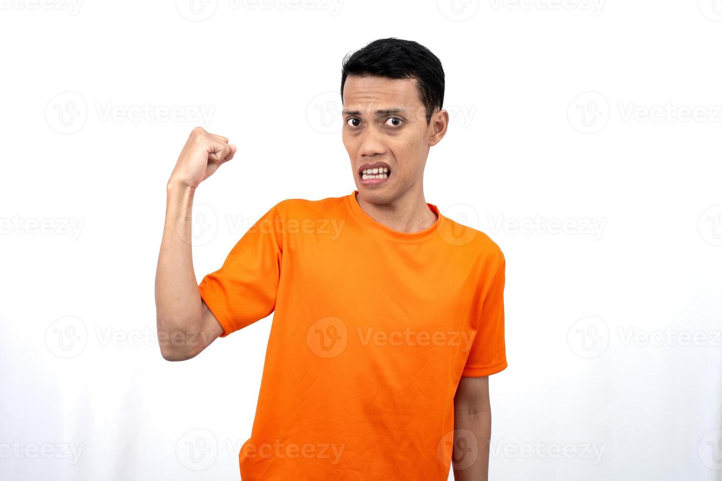 Portrait of a young Asian man wearing an orange t-shirt with a happy expression, surprised to get good news. Isolated on white background. photo