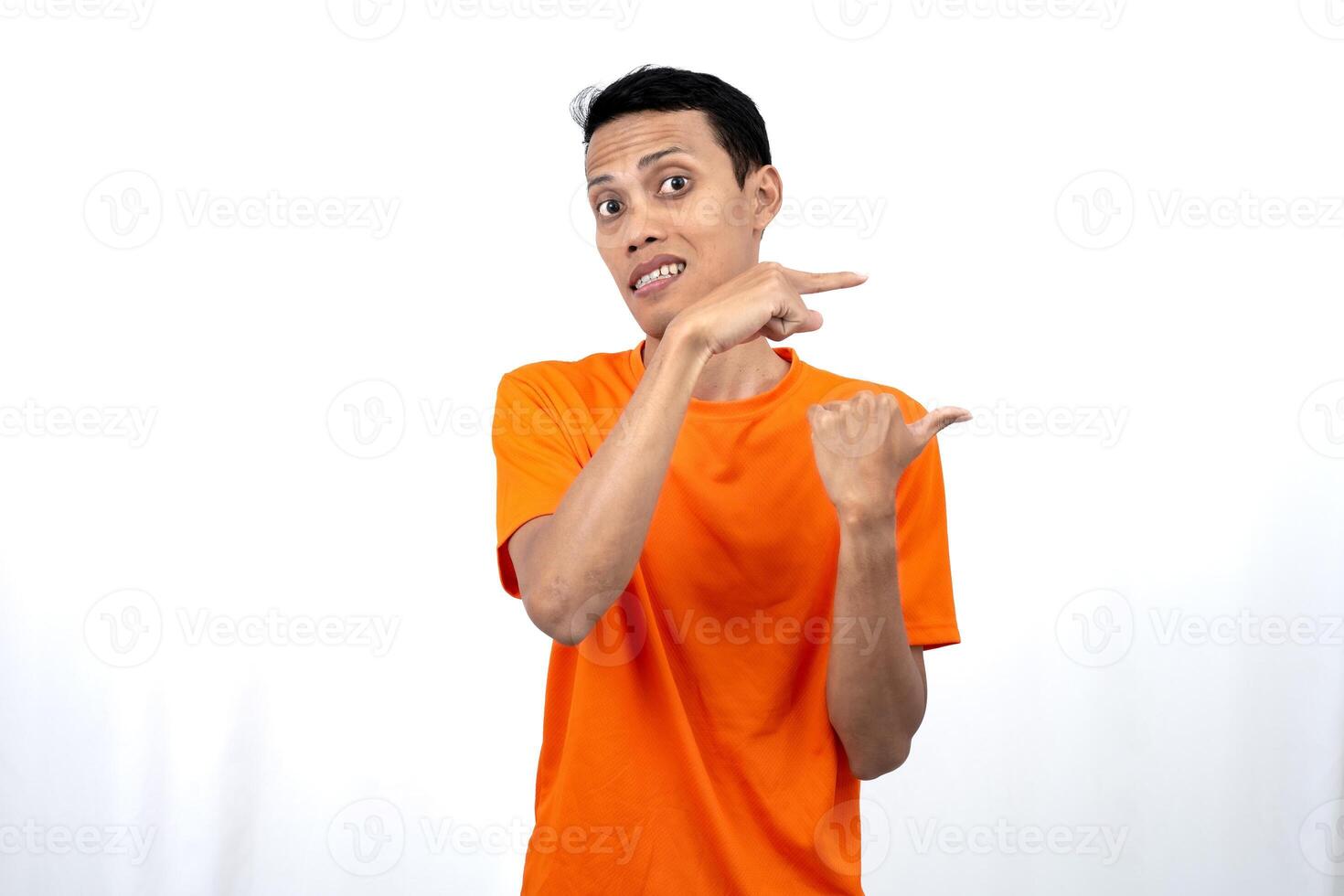 Portrait of a young Asian man wearing an orange t-shirt pointing aside copy space for promotional space. isolated on white background. photo