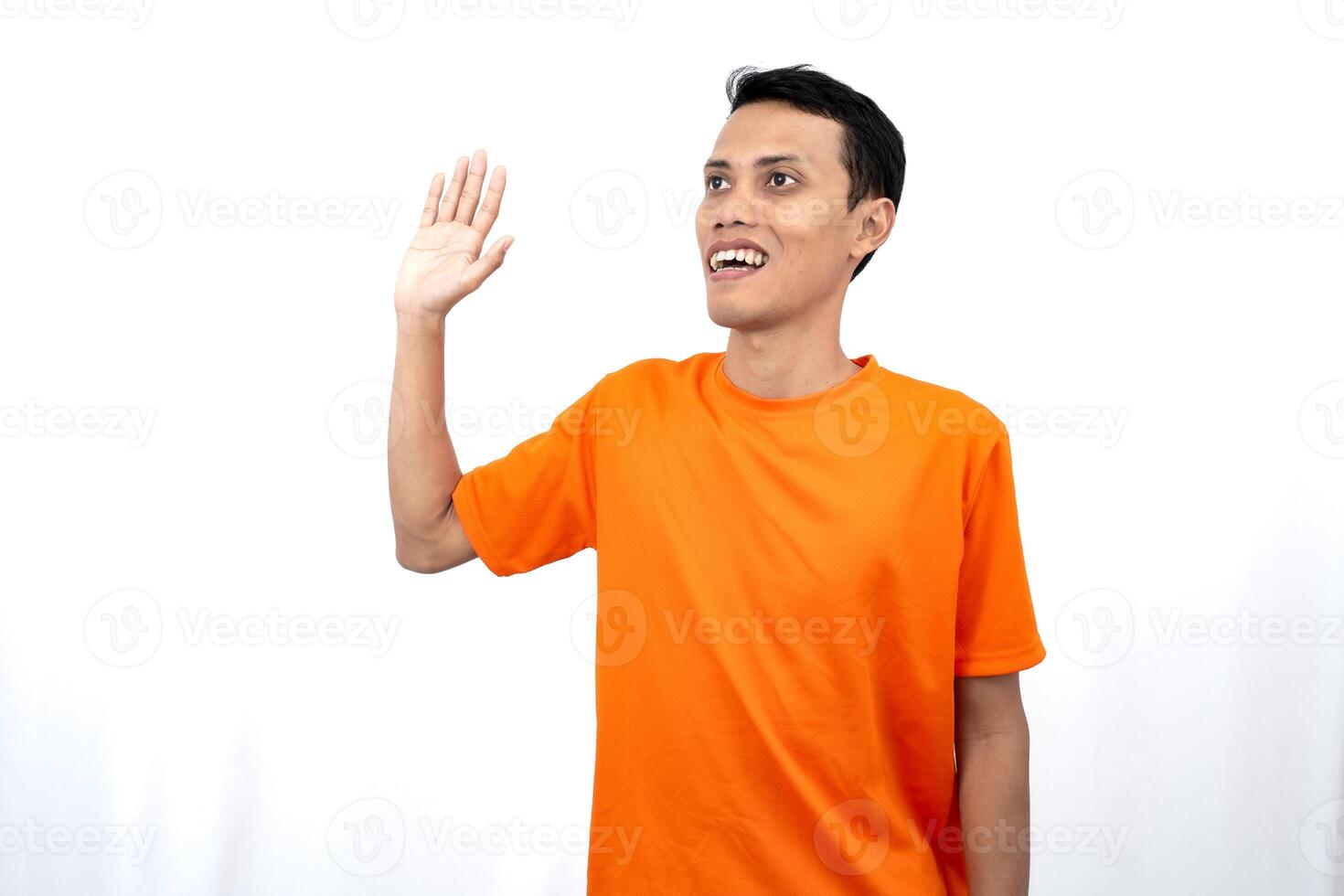 Portrait of a young Asian man wearing an orange t-shirt posing giving a warm greeting to a friend or customer. Isolated on white background. photo