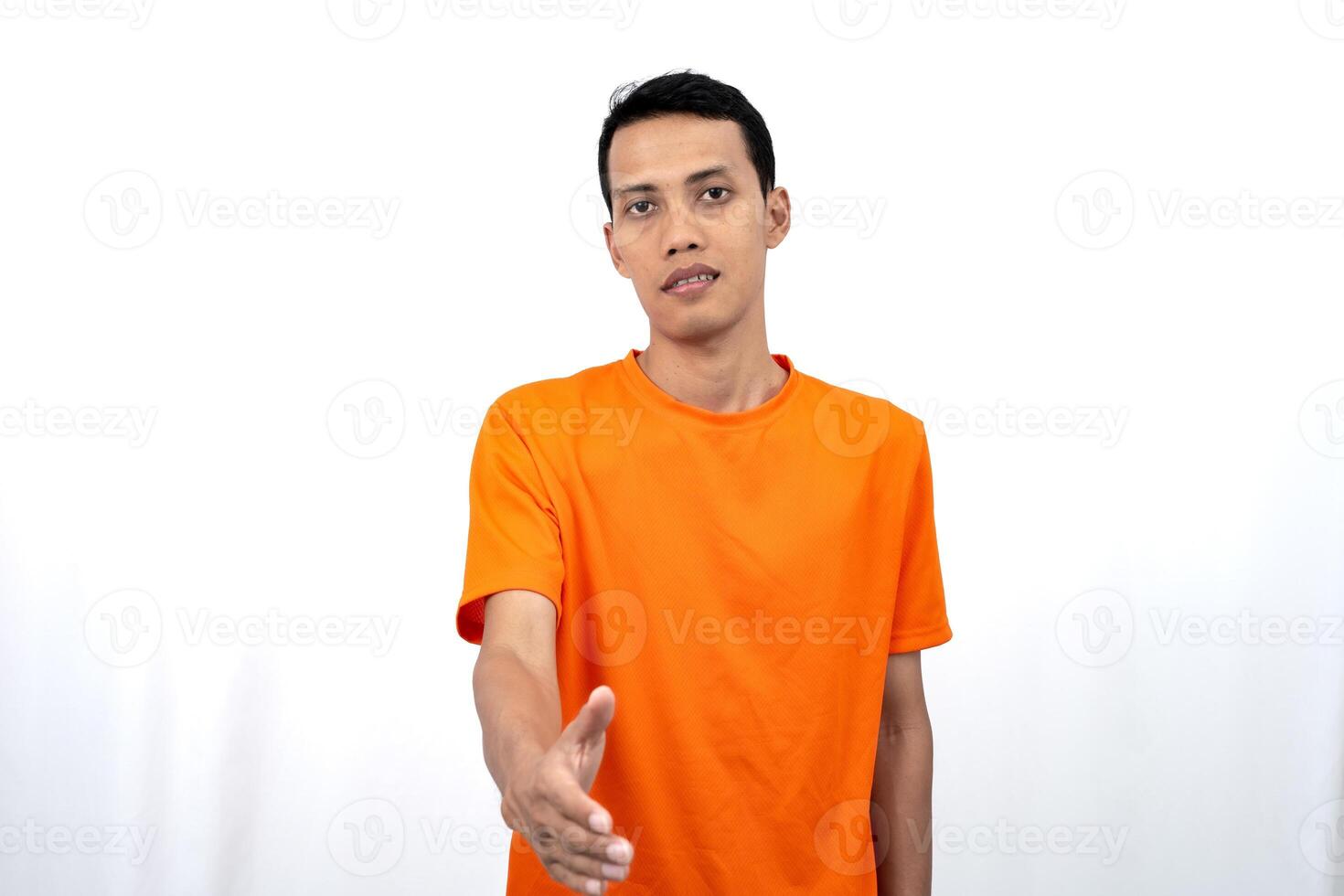 Portrait of a young Asian man wearing an orange t-shirt posing giving a warm greeting to a friend or customer. Isolated on white background. photo