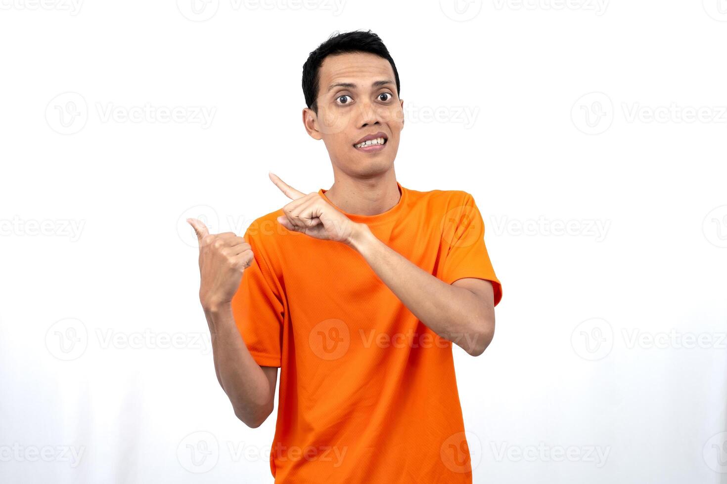 Portrait of a young Asian man wearing an orange t-shirt pointing aside copy space for promotional space. isolated on white background. photo