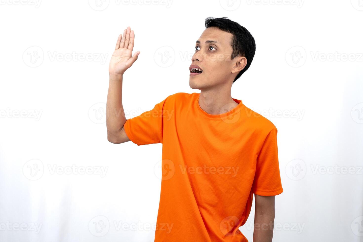 Portrait of a young Asian man wearing an orange t-shirt posing giving a warm greeting to a friend or customer. Isolated on white background. photo