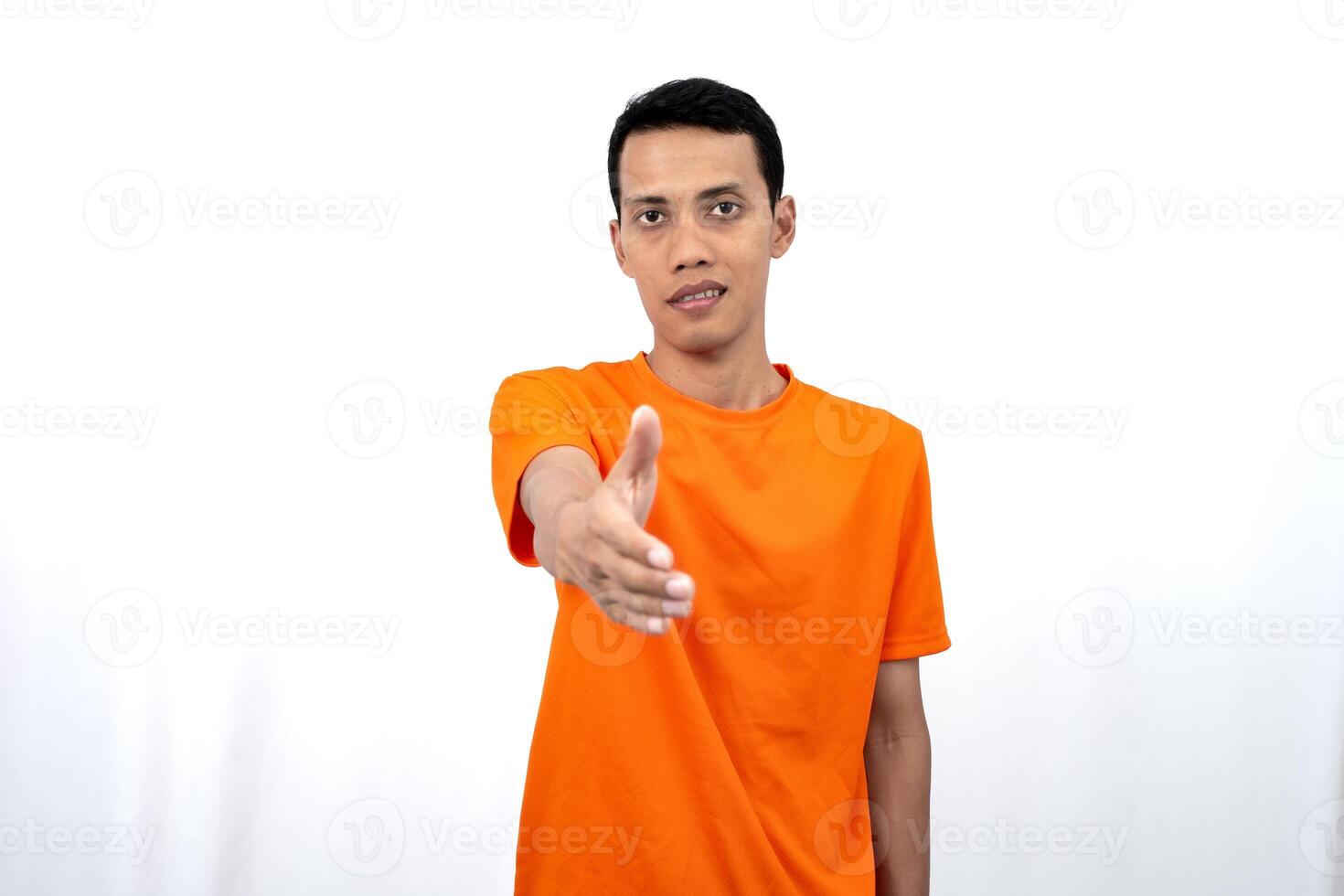 Portrait of a young Asian man wearing an orange t-shirt posing giving a warm greeting to a friend or customer. Isolated on white background. photo