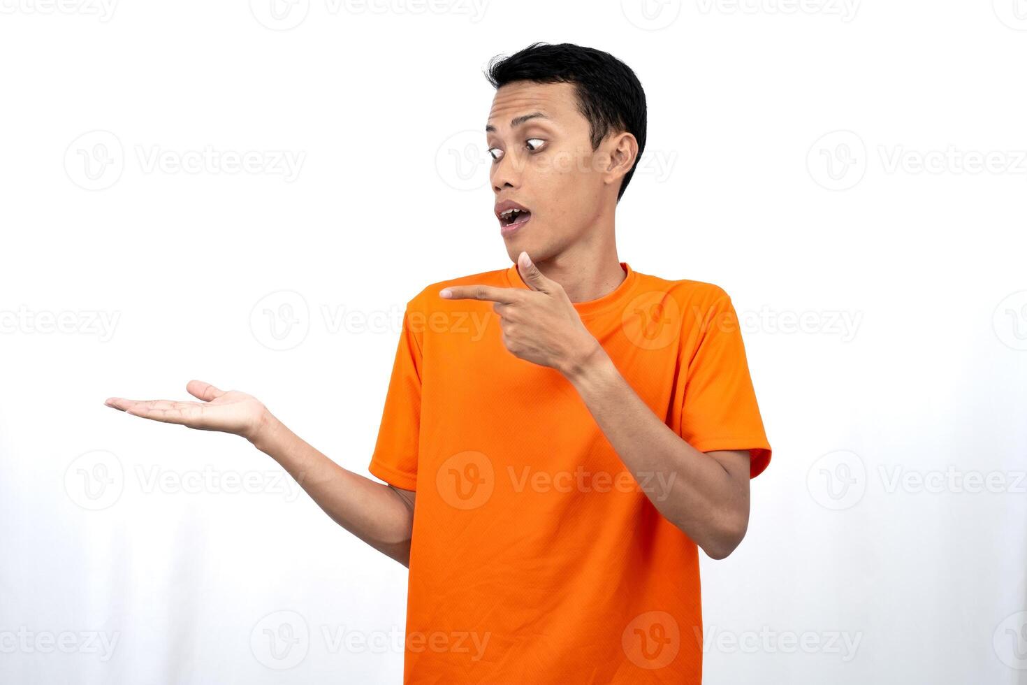 Portrait of a young Asian man wearing an orange t-shirt pointing aside copy space for promotional space. isolated on white background. photo