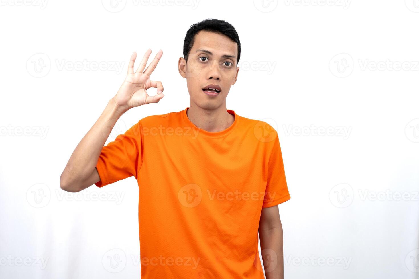 Portrait of a young Asian man wearing an orange t-shirt giving a thumbs up, okay, agree sign. isolated on white background. photo
