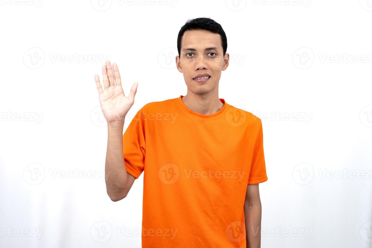 Portrait of a young Asian man wearing an orange t-shirt posing giving a warm greeting to a friend or customer. Isolated on white background. photo