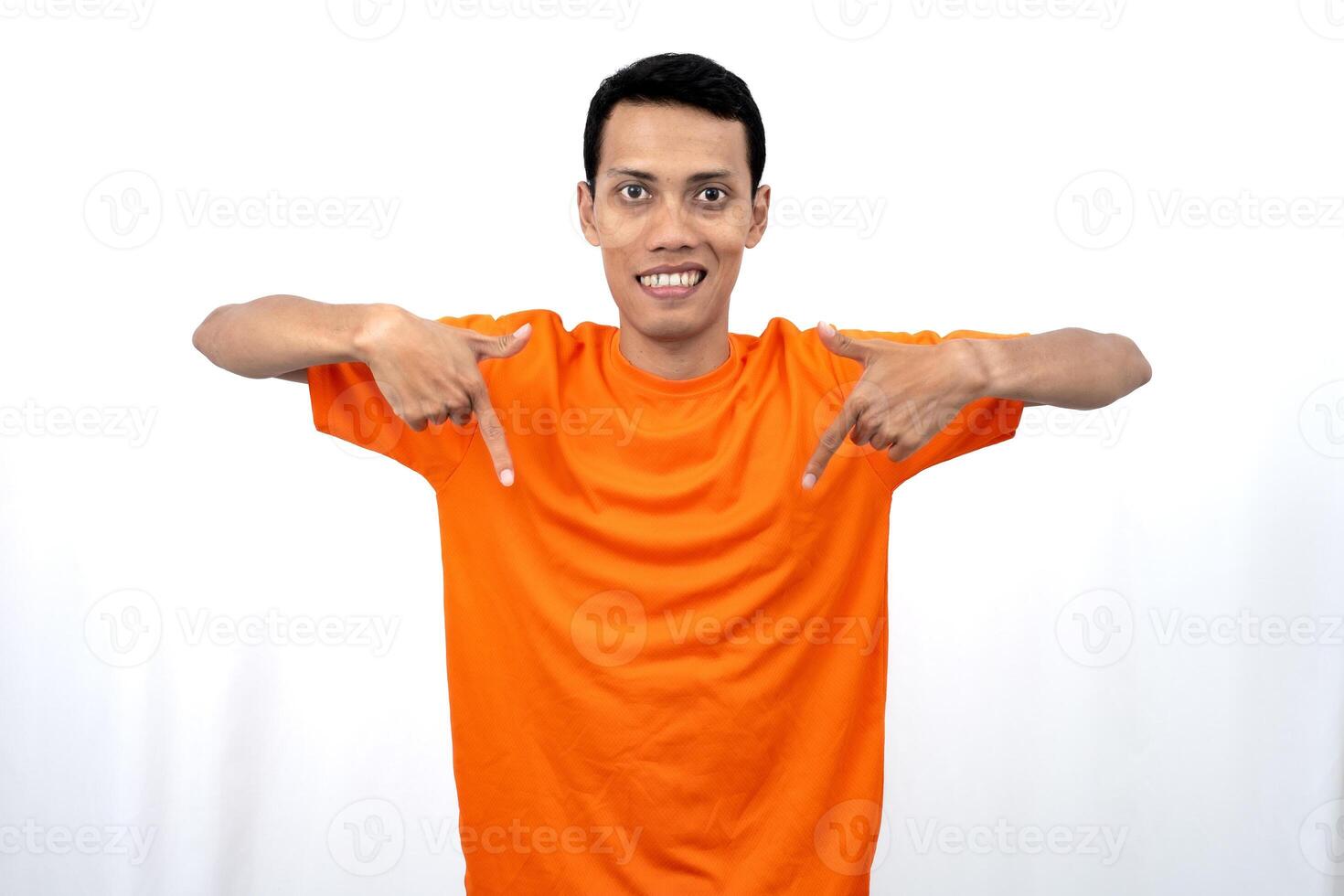 Portrait of a young Asian man wearing an orange t-shirt pointing down copy space for promotional space. isolated on white background. photo