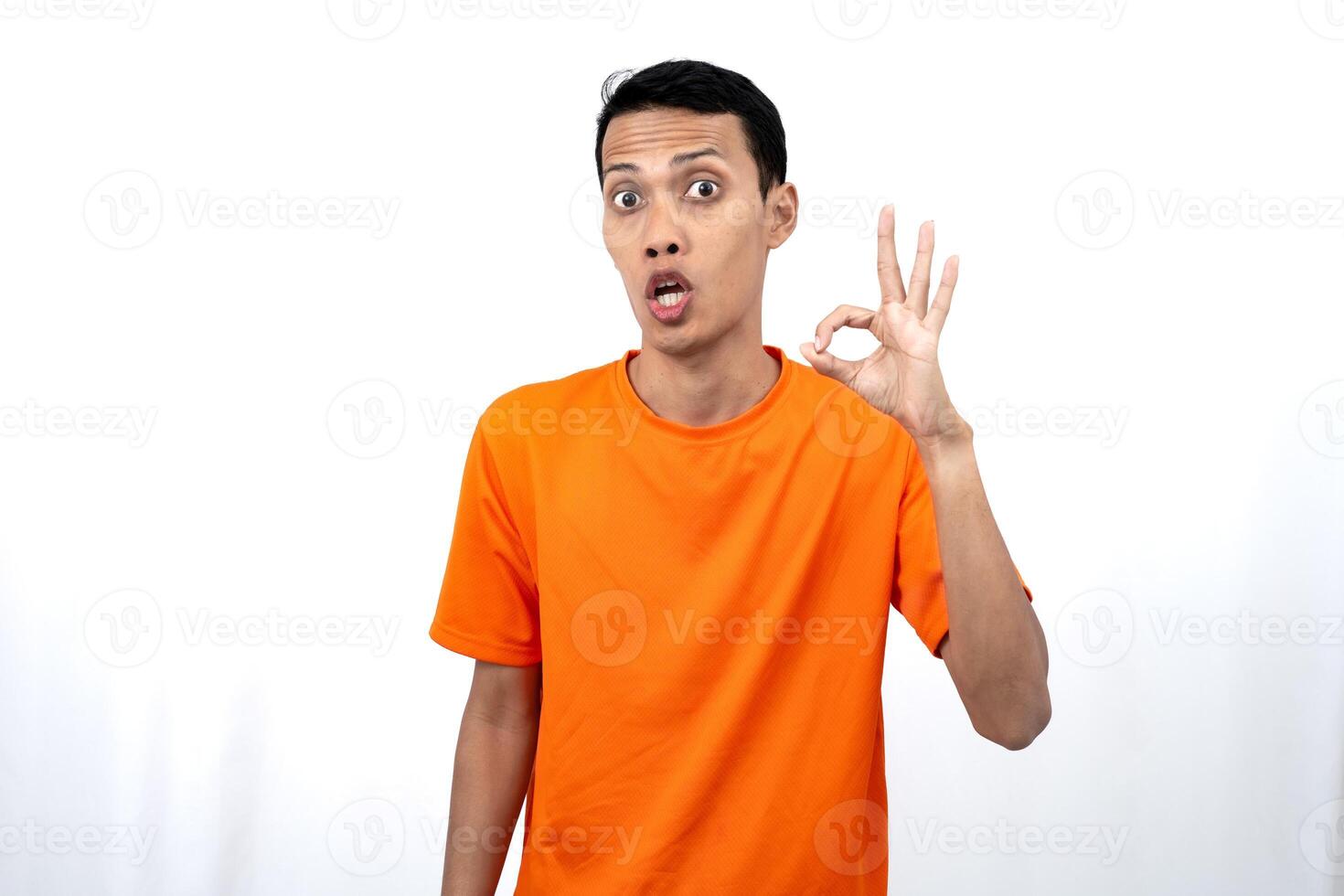 Portrait of a young Asian man wearing an orange t-shirt giving a thumbs up, okay, agree sign. isolated on white background. photo