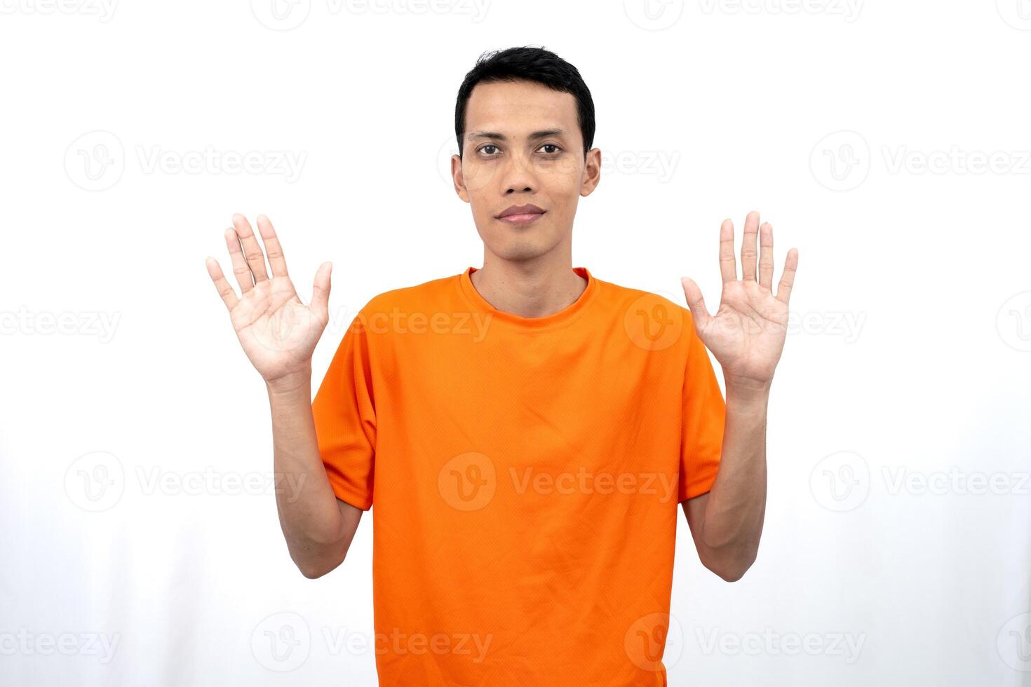 Portrait of a young Asian man wearing an orange t-shirt posing giving a warm greeting to a friend or customer. Isolated on white background. photo