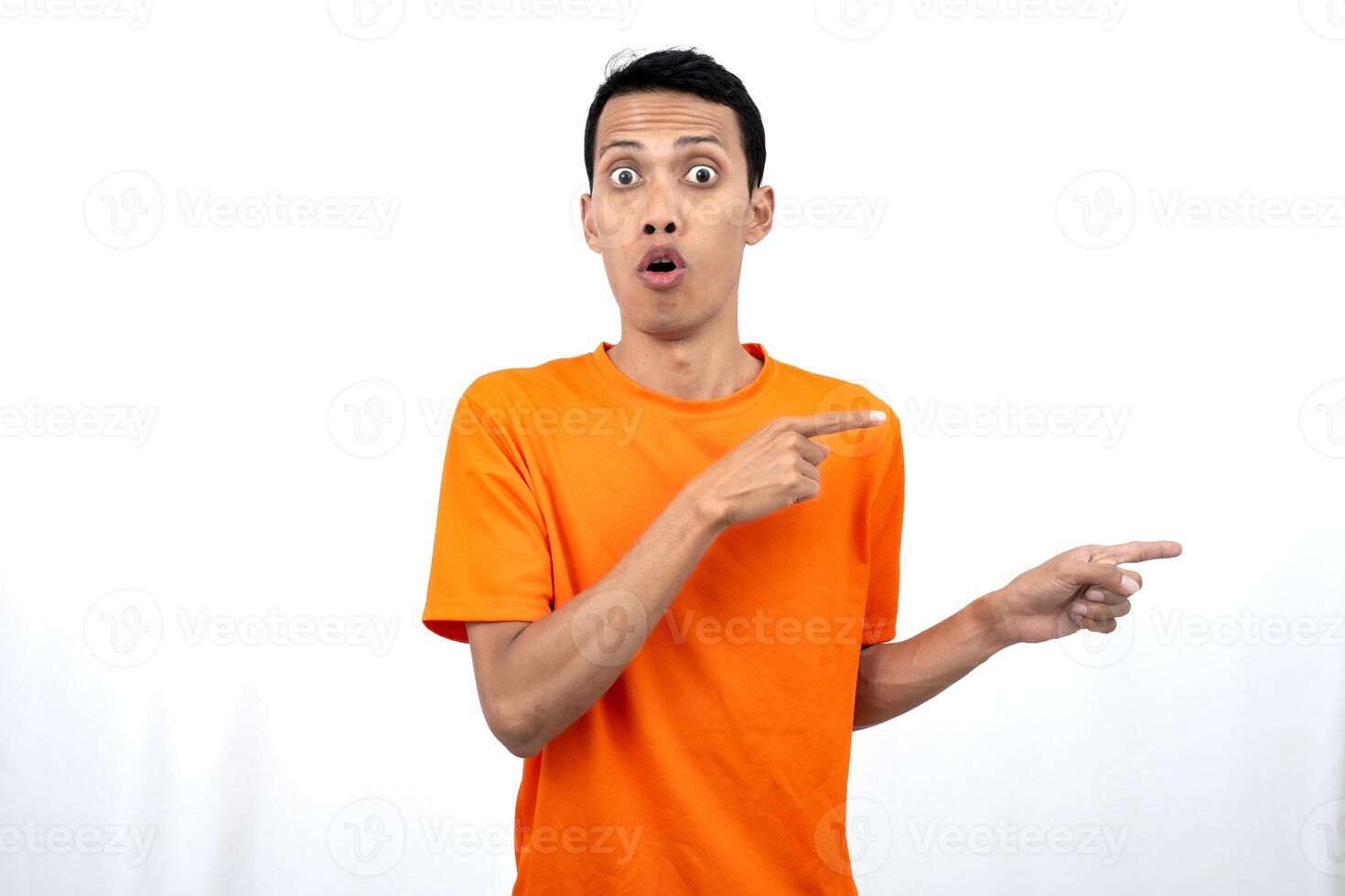 Portrait of a young Asian man wearing an orange t-shirt pointing aside copy space for promotional space. isolated on white background. photo