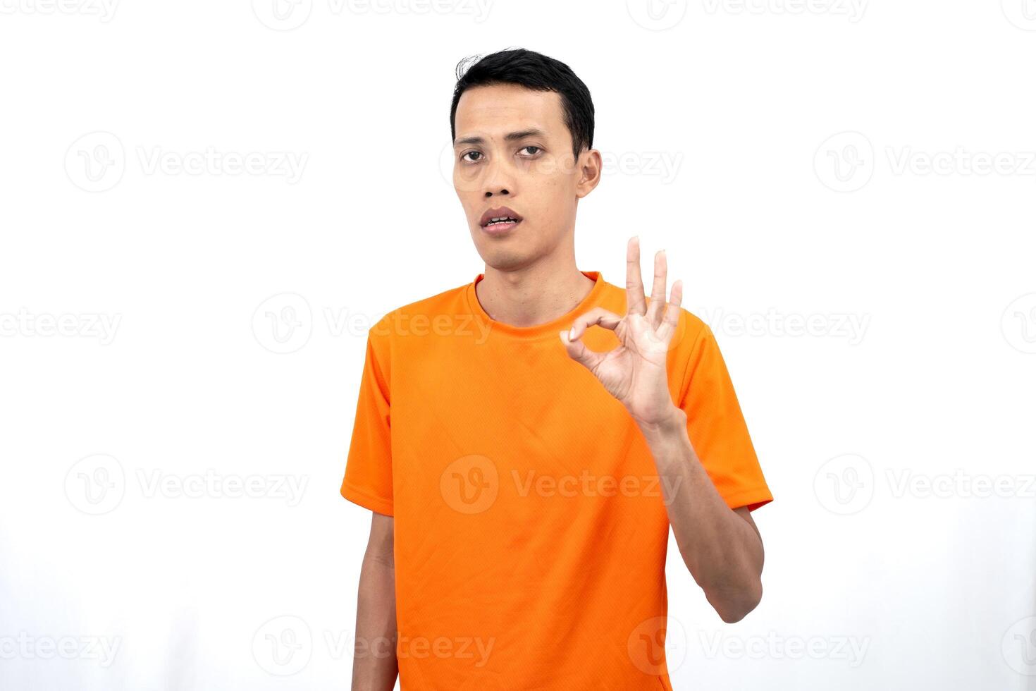 Portrait of a young Asian man wearing an orange t-shirt giving a thumbs up, okay, agree sign. isolated on white background. photo