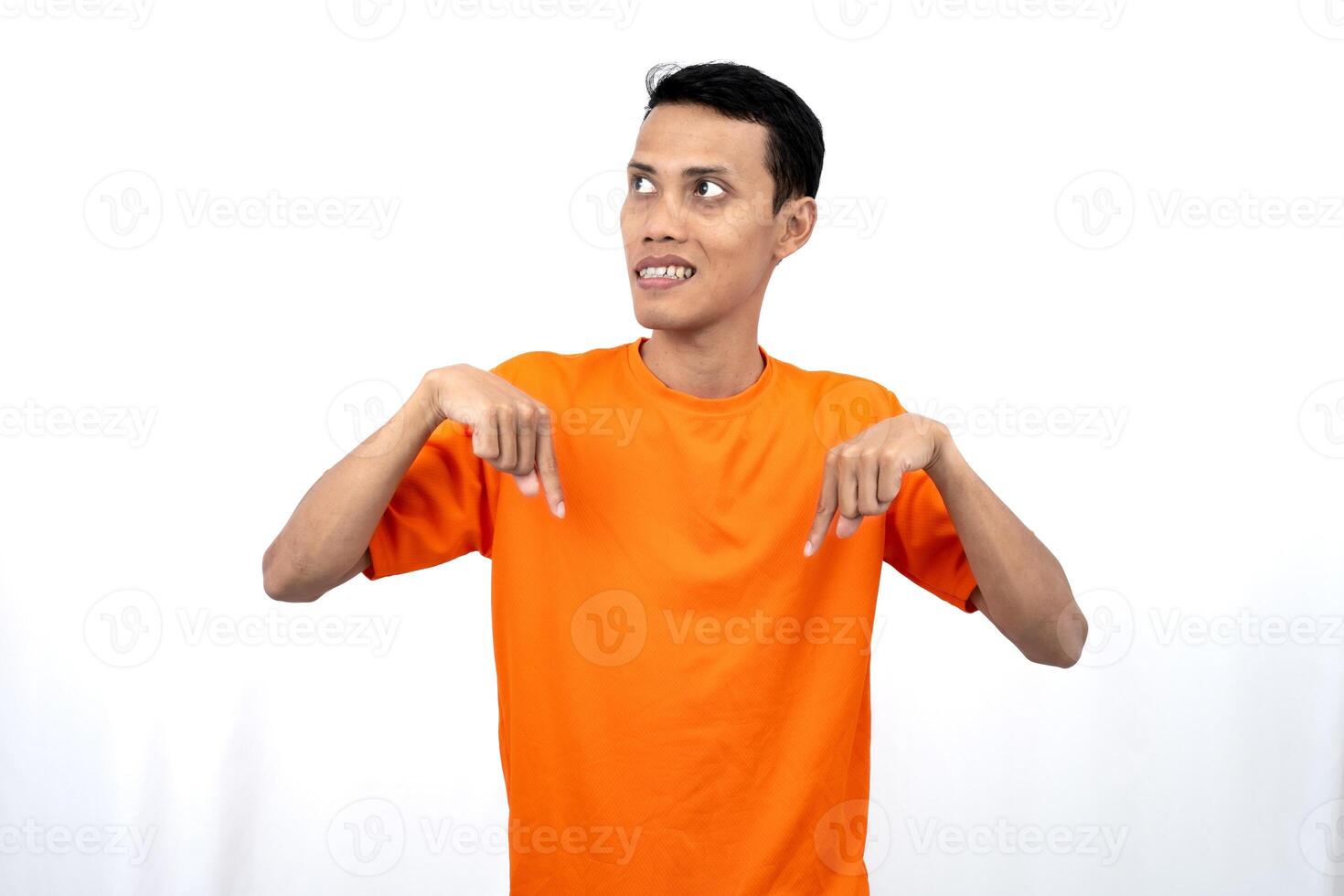 Portrait of a young Asian man wearing an orange t-shirt pointing down copy space for promotional space. isolated on white background. photo