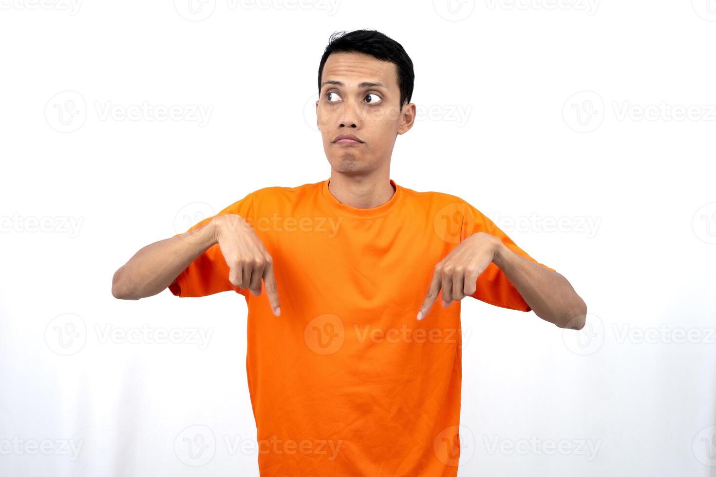 Portrait of a young Asian man wearing an orange t-shirt pointing down copy space for promotional space. isolated on white background. photo
