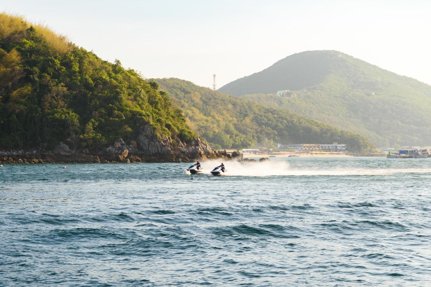 Pattaya, Thailand - March 7, 2024, Man driving a jet ski on Blue sea at Koh Larn island on sunset sky background. Group of Tourist or Traveler on the beach. Vacation, Summer, Holiday, Relax, Activity. photo