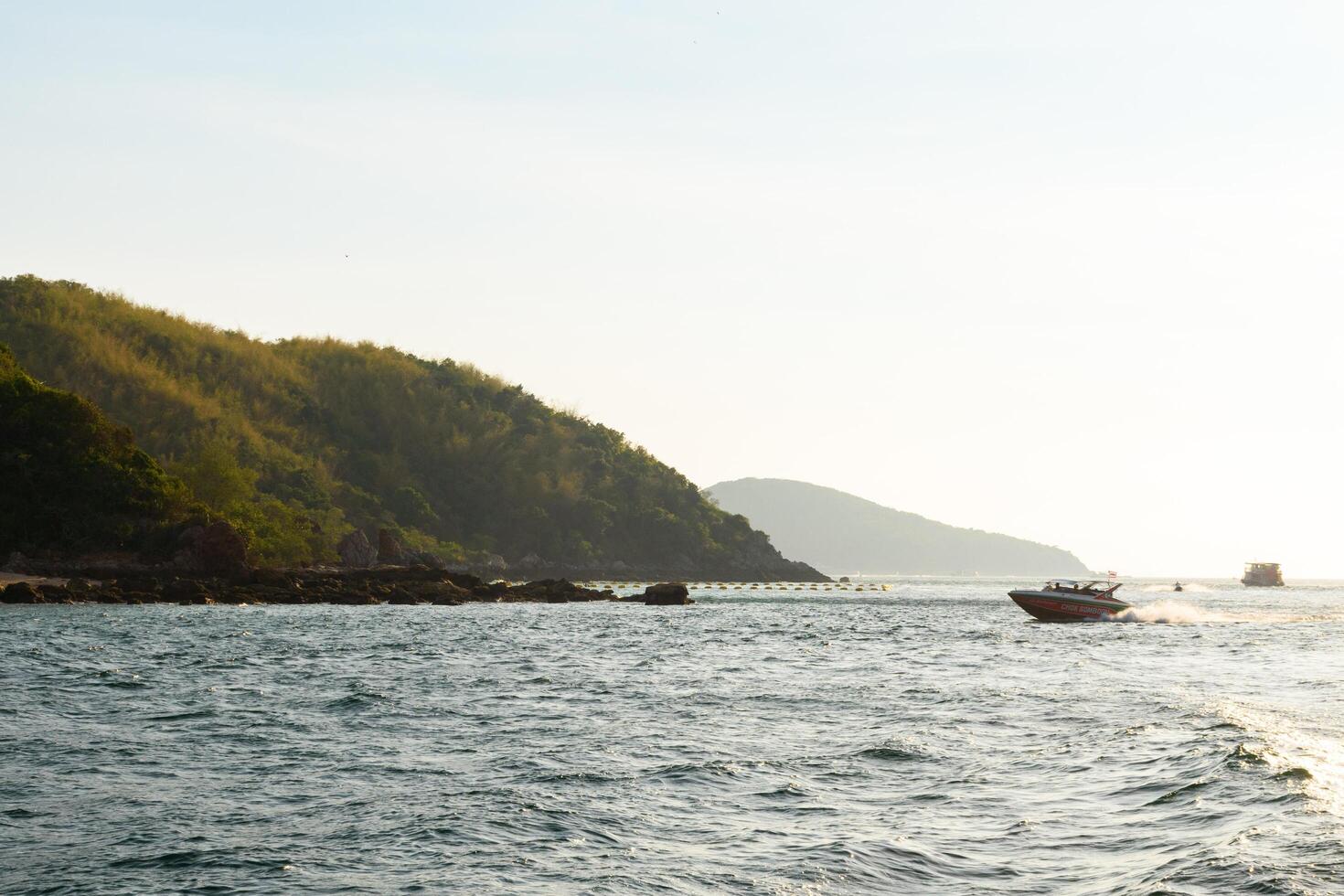 Pattaya, Thailand - March 7, 2024, Speedboat or Ship on Blue sea at Koh Larn island on sunset sky background. Group of Tourist or Traveler on the beach. Vacation, Summer, Holiday, Relax, Activity. photo