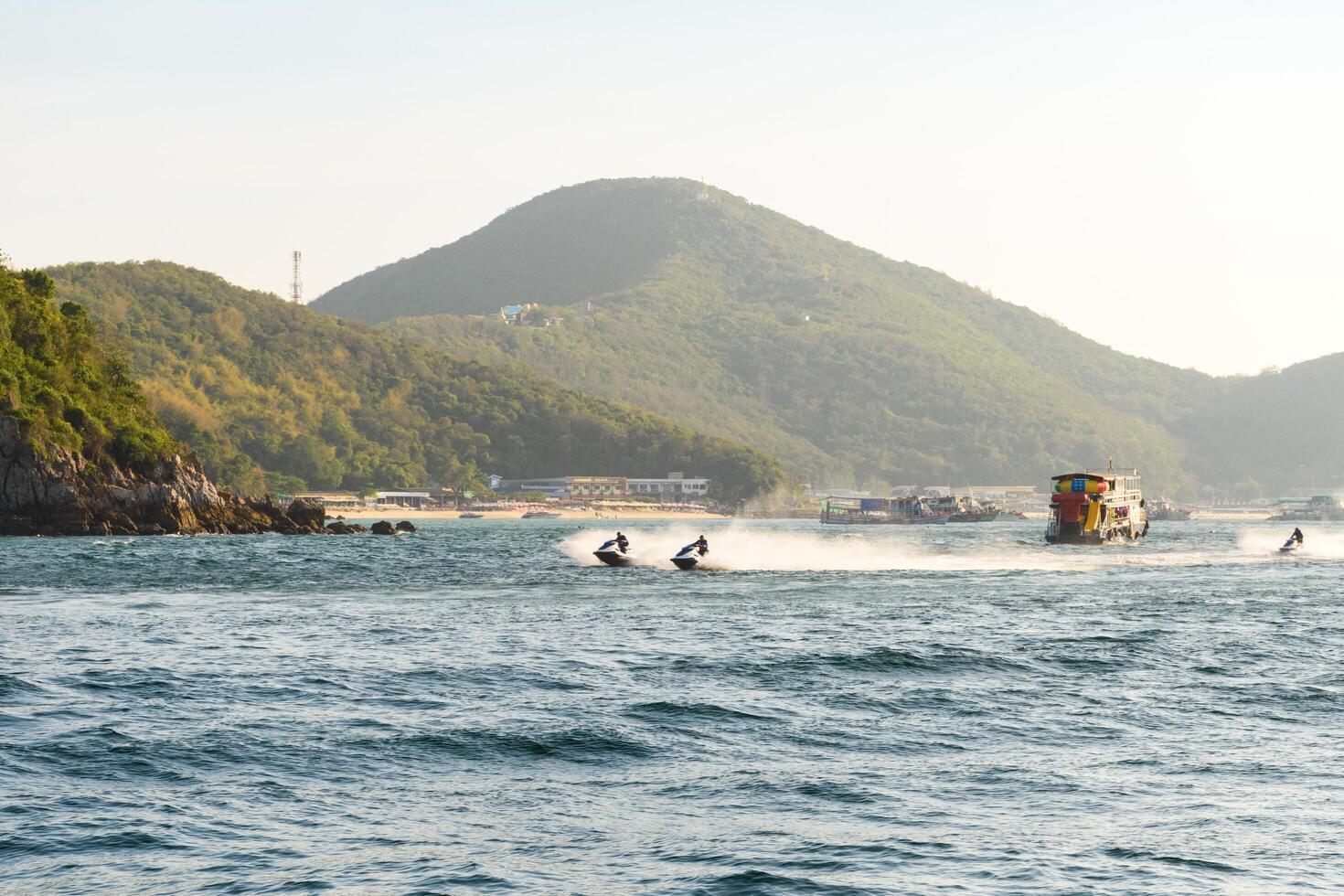 Pattaya, Thailand - March 7, 2024, Man driving a jet ski on Blue sea at Koh Larn island on sunset sky background. Group of Tourist or Traveler on the beach. Vacation, Summer, Holiday, Relax, Activity. photo