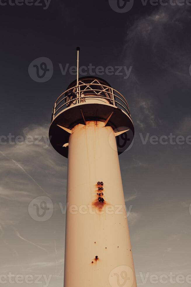 White lighthouse with a dark sky on the background photo