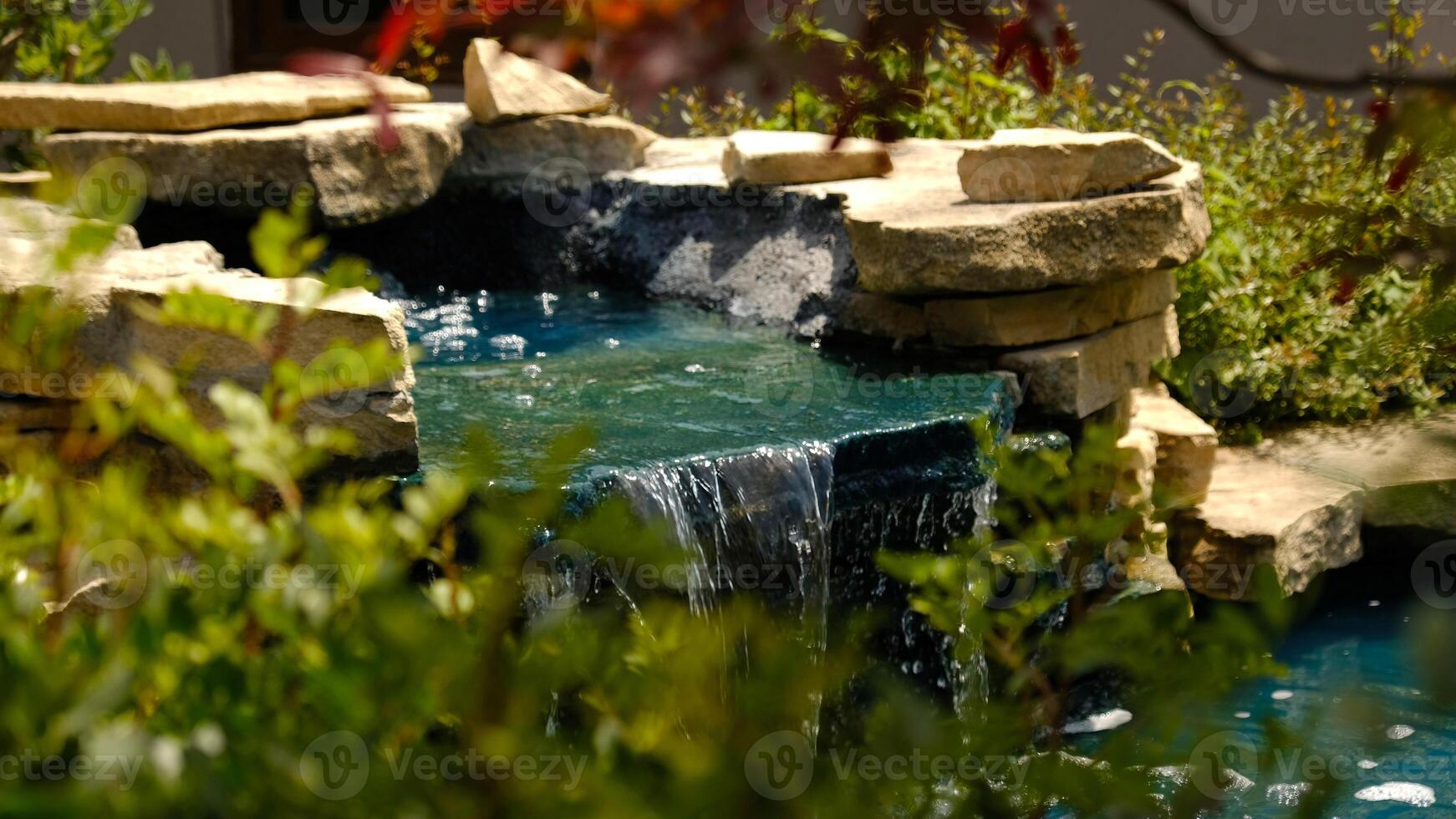 A mini waterfall in a traditional Japanese garden. Decorative waterfall made of stones and a small pond for landscape design. photo