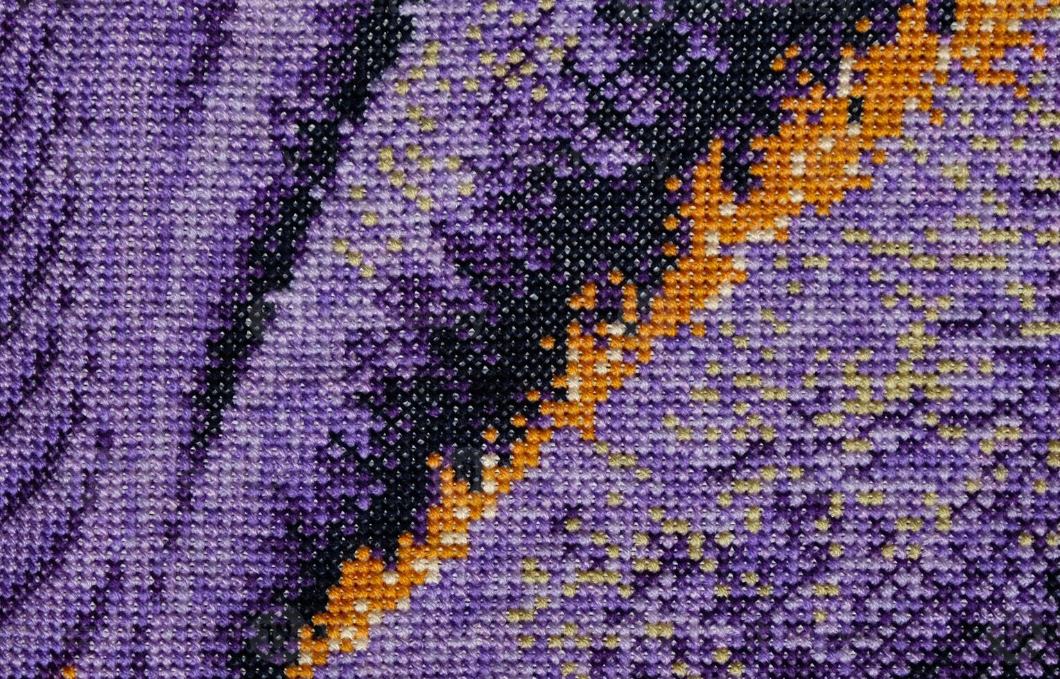 Purple, violet and brown close-up cross stitch background. Abstract Embroidered handmade Pattern. Needlework and DIY concept. Top view, macro, flat lay, mockup. photo