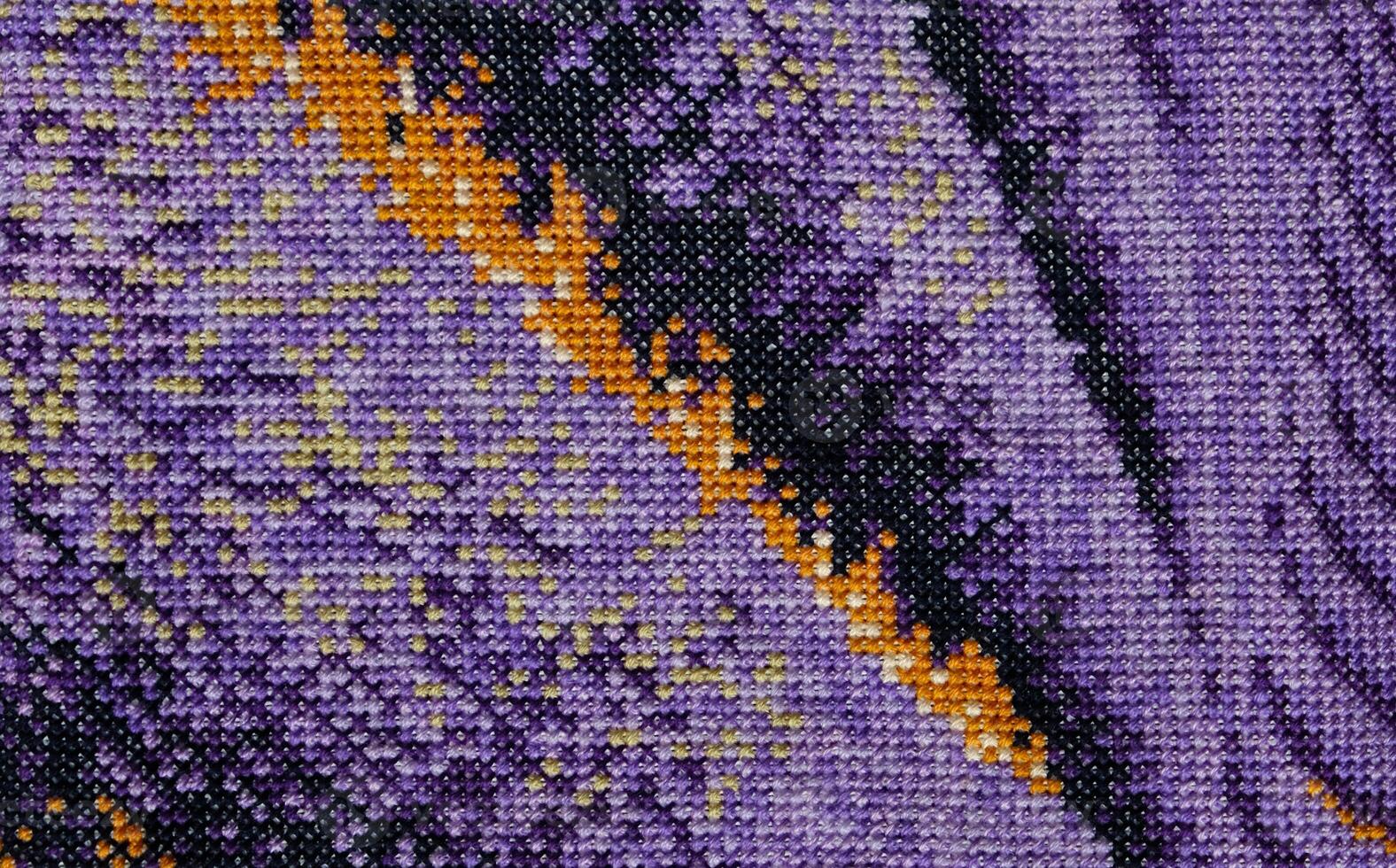 Purple, violet and brown close-up cross stitch background. Abstract Embroidered handmade Pattern. Needlework and DIY concept. Top view, macro, flat lay, mockup. photo
