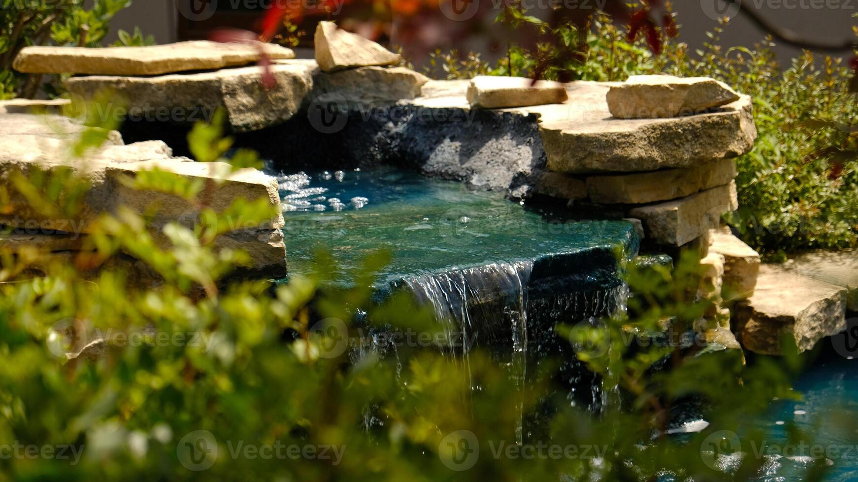 A mini waterfall in a traditional Japanese garden. Decorative waterfall made of stones and a small pond for landscape design. photo