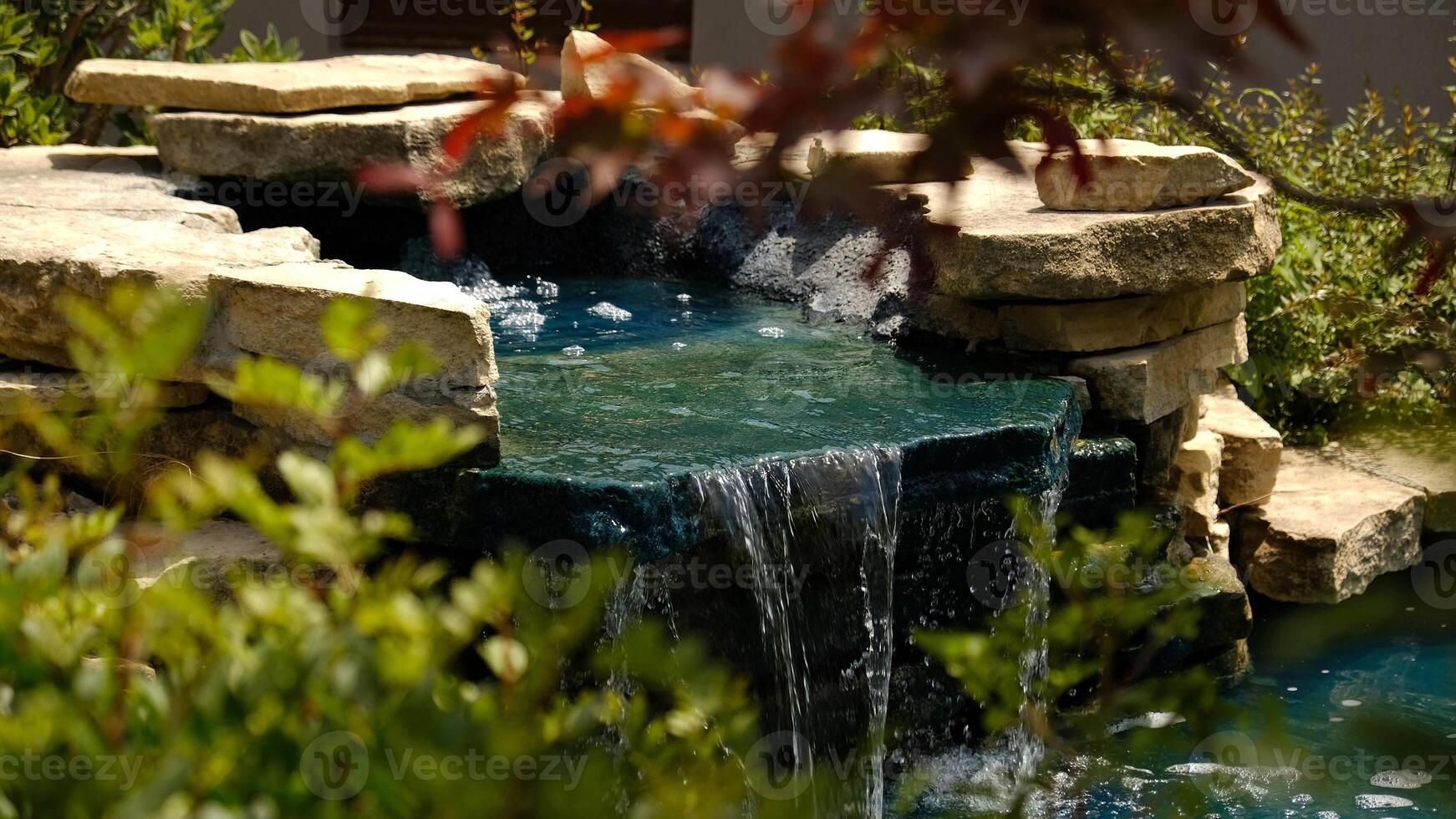 A mini waterfall in a traditional Japanese garden. Decorative waterfall made of stones and a small pond for landscape design. photo