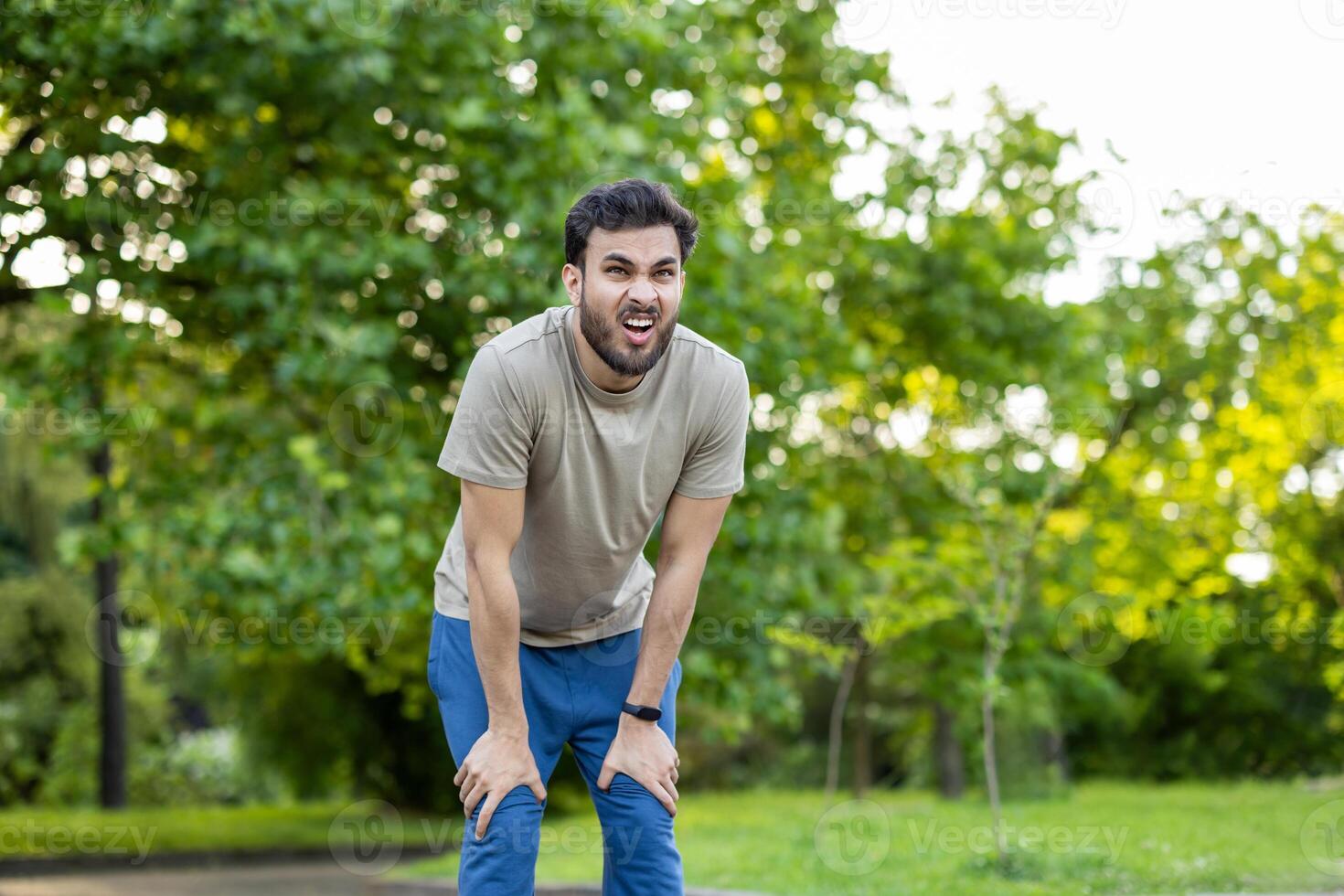 Young athlete pauses to catch breath after outdoor fitness session in vibrant green park. Expression of determination and challenge highlights physical endurance and mental resilience. photo