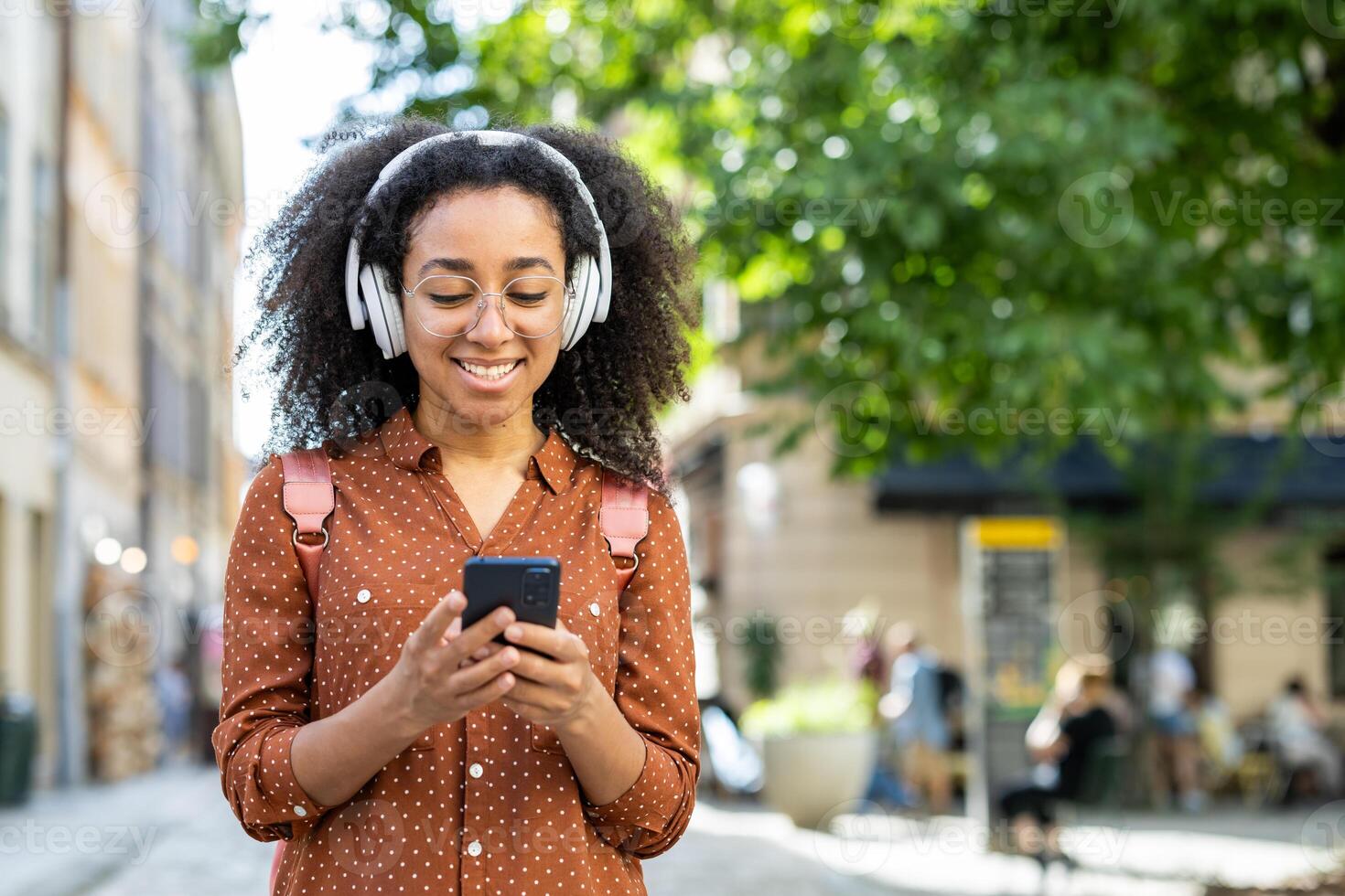 Woman tourist wearing headphones and using a smartphone while strolling through the city on vacation. The image captures a sense of joy and relaxation as she enjoys her surroundings. photo